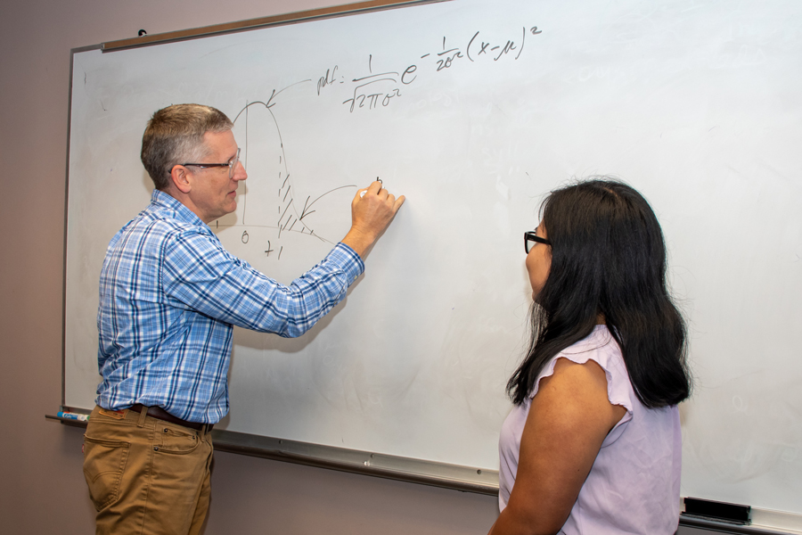 FSU Sociology instructor working with a female student on a white board