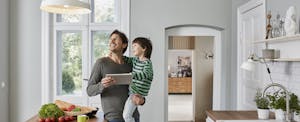 Father and son using tablet in kitchen looking at ceiling lamp