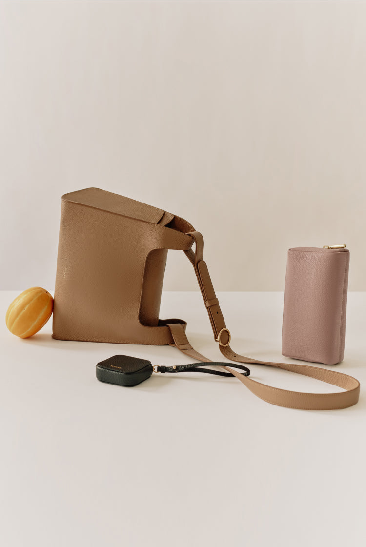 A bag, wallet, small object, and cable clip arranged on a table.