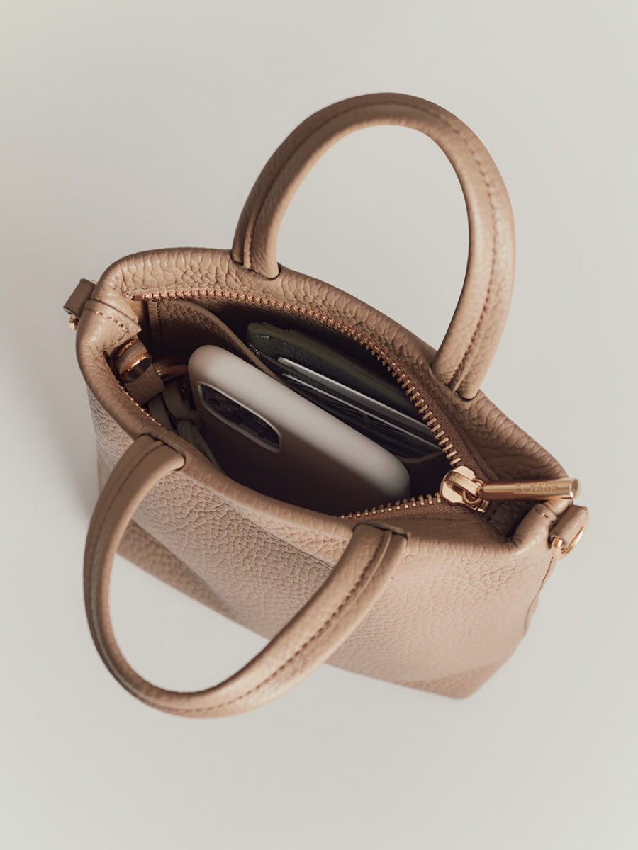 Open handbag with smartphone and sunglasses inside.