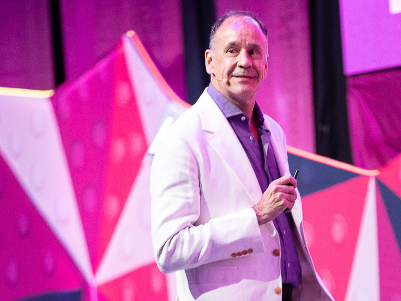 An image of Jaime Vall&eacute;s, Vice President, AWS Global Sales for APJ, as he's giving a speaking presentation from a stage in front of a bright pink backdrop.