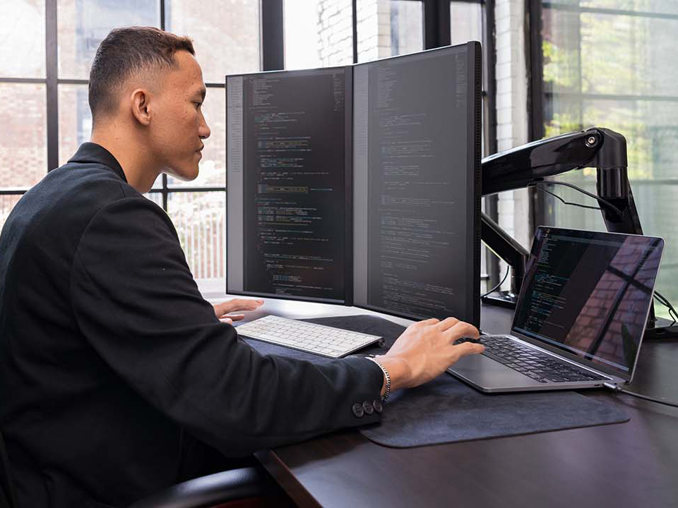 software engineer working on code on three screens