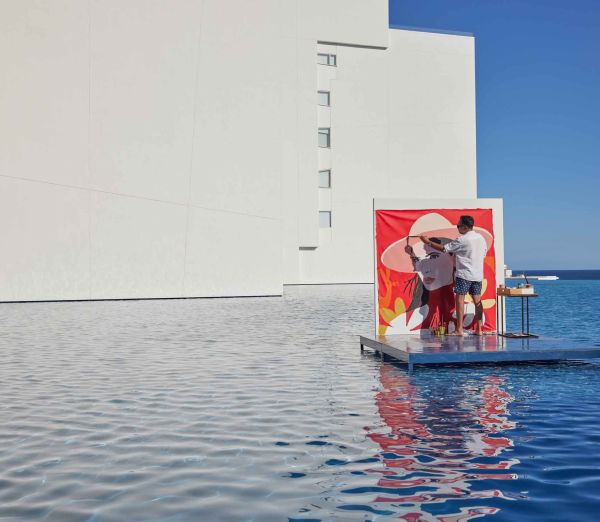 A Couple Of People Standing On A Platform In The Water By A Building