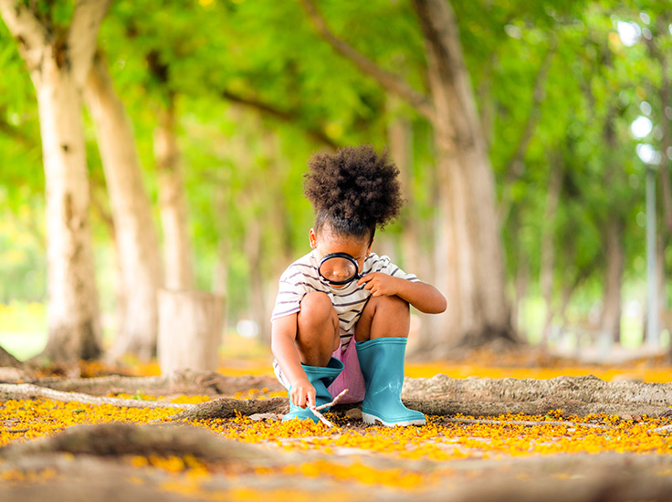 Criança com lupa explorando a natureza