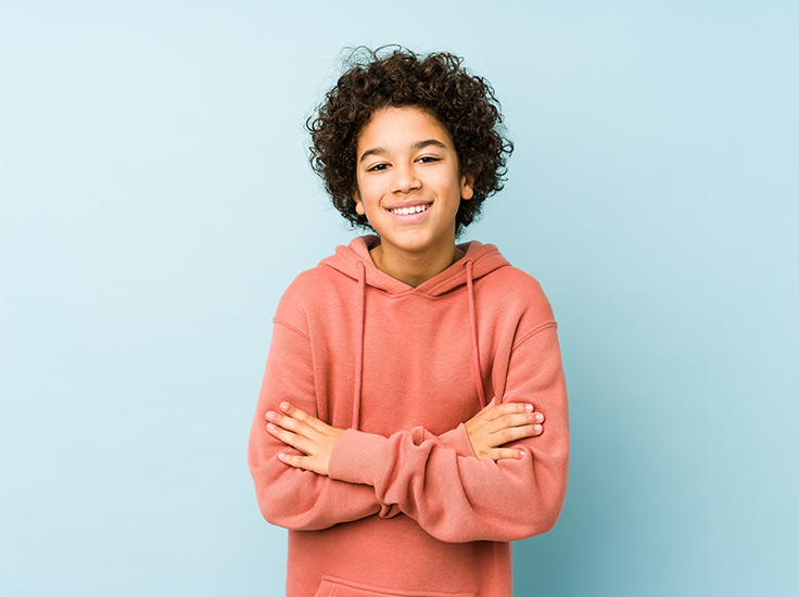 Menino sorrindo de braços cruzados