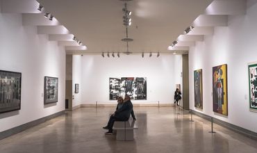 Sala de museu com quadros na parede.