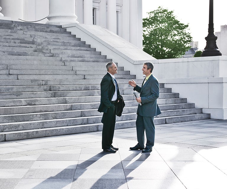 two business men talking by the office stairs