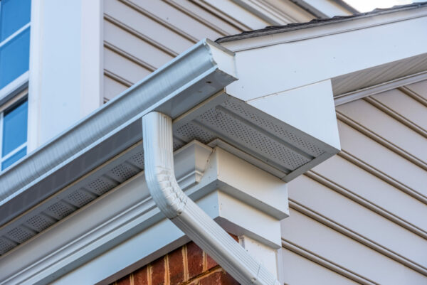 Close up of white frame gutter guard system,decorative trim, eaves through, fascia, drip edge, colonial white soffit with ventilation, luxury American single family home neighborhood USA