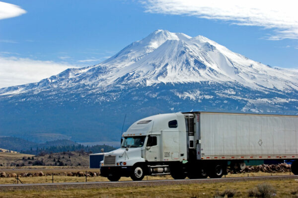 semi truck driving on a road with a mountain in the background