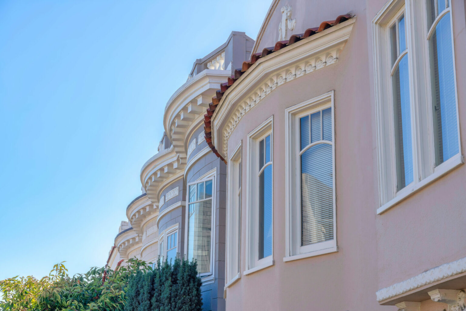 Houses with frieze and corbels in San Francisco, California. There is a residential building at the back with white corbel roofs beside the building at the front with frieze board at the window.