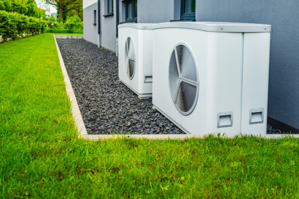 Two air source heat pumps installed outside of house
