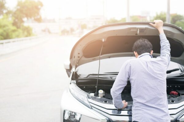 Man looking at his broken down car wishing he had an extended car warranty