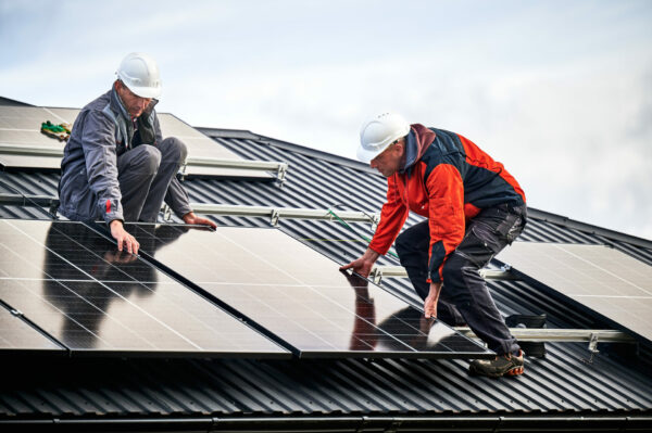 two men installing solar panels on home roof