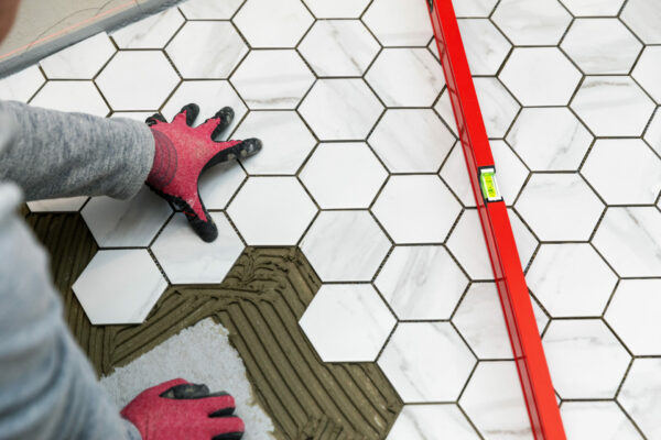 tiler laying marble texture hexagon tiles on the bathroom floor