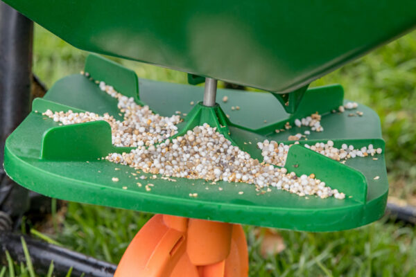 Closeup of lawn fertilizer spreader with granules of weed killer herbicide