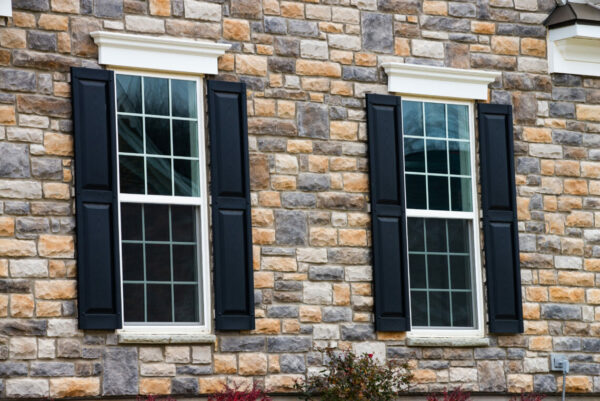 two pane vinyl window with shutters on a vinyl siding house closeup