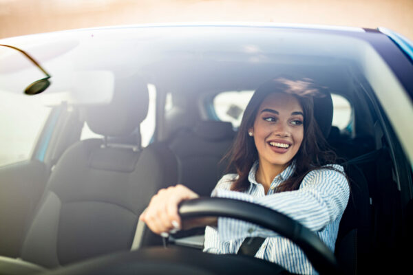 Portrait of happy brunette woman steering car