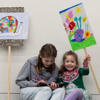 Two children displaying artworks they have created