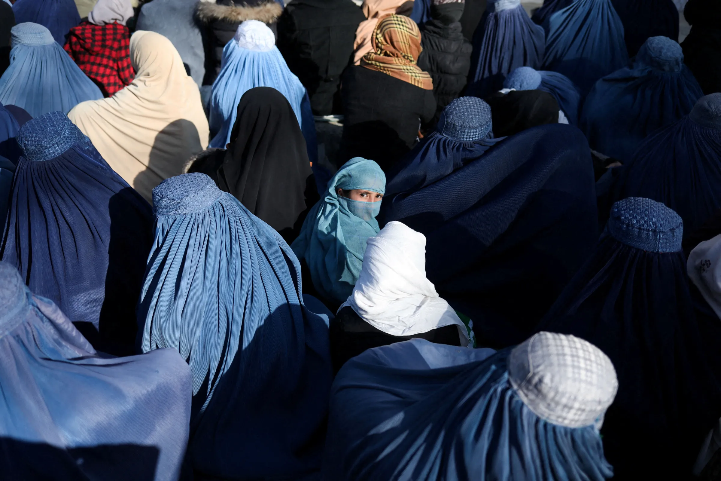 A girl sits in front of a bakery in the crowd with Afghan women waiting to receive bread in Kabul, Afghanistan, January 31, 2022. REUTERS/Ali Khara