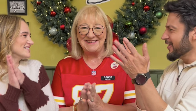 Donna Kelce wears a Kansas City Chiefs jersey in a restaurant decorated for Christmas with her 'Holiday Touchdown' co-stars Hunter King and Tyler Hynes