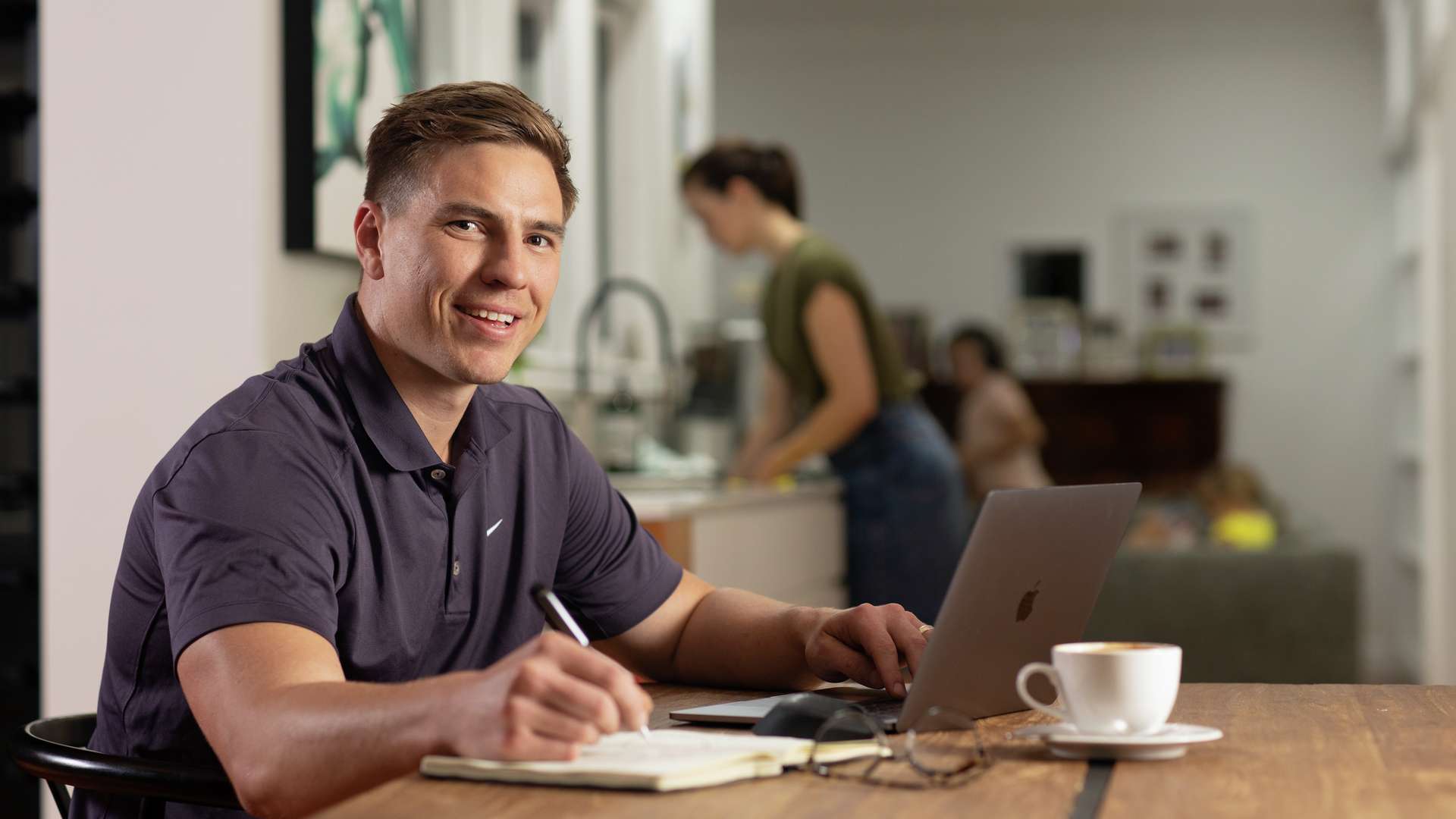 Man studying online with laptop at a dining table with coffee