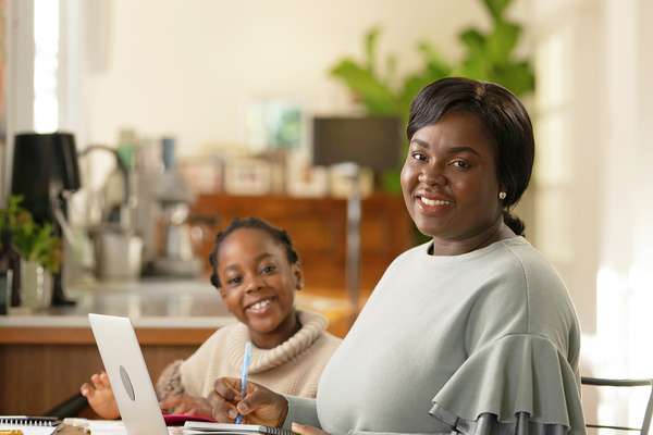 A parent student with their child at the table smiling at the camera.