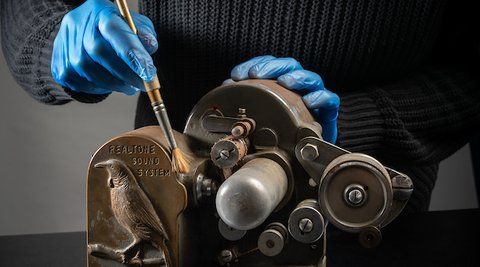 Worker cleaning an antique sound projector