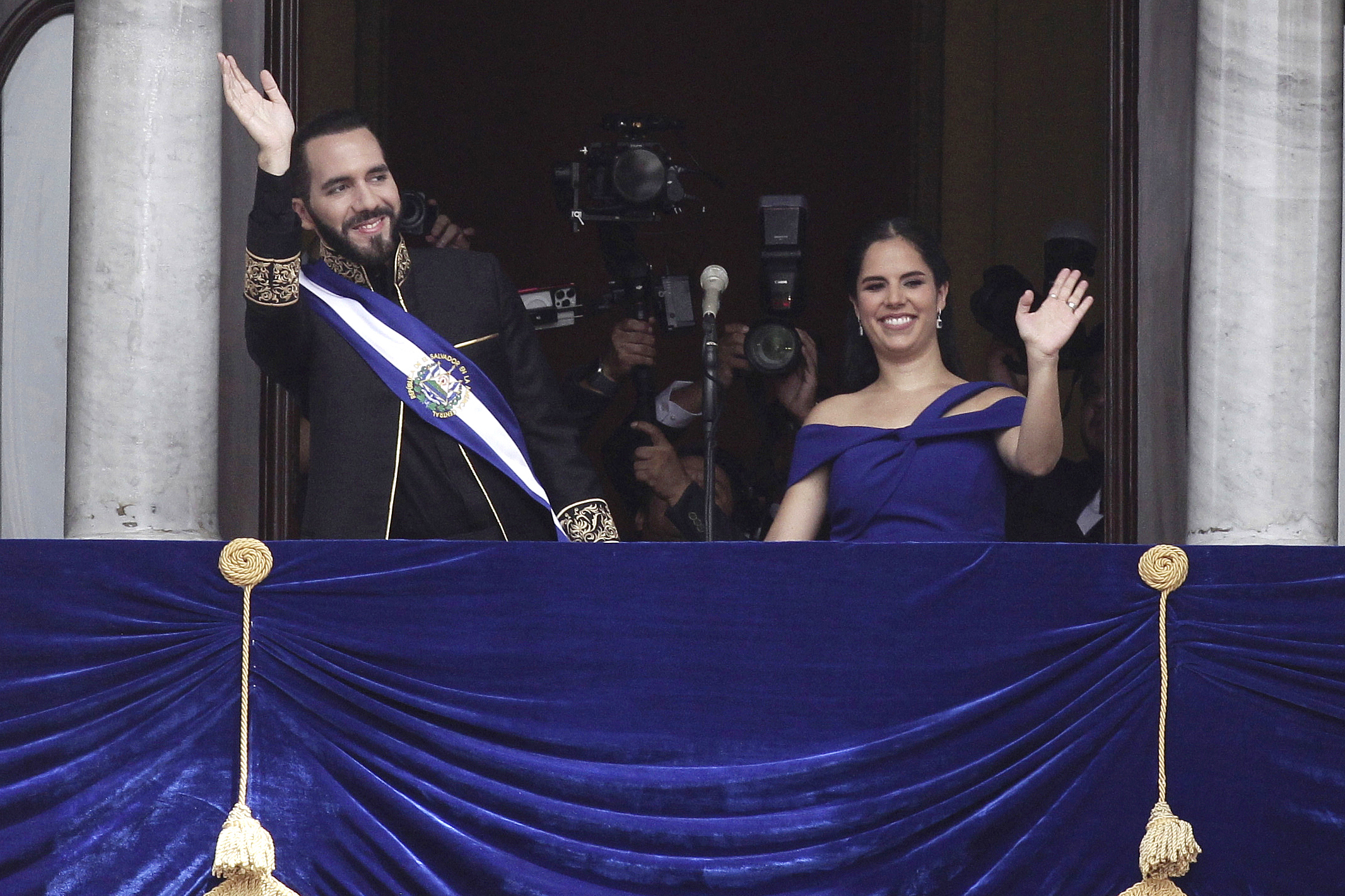 FILE - El Salvador's President Nayib Bukele and first lady Gabriela Roberta Rodríguez wave from a balcony after he was sworn in for a second term, in San Salvador, El Salvador, June 1, 2024. Known for his heavy-handed crackdown on street gangs, threatened to use similar tactics against price gougers, Bukele said in a speech late Friday, July 5. (AP Photo/Salvador Melendez, File)