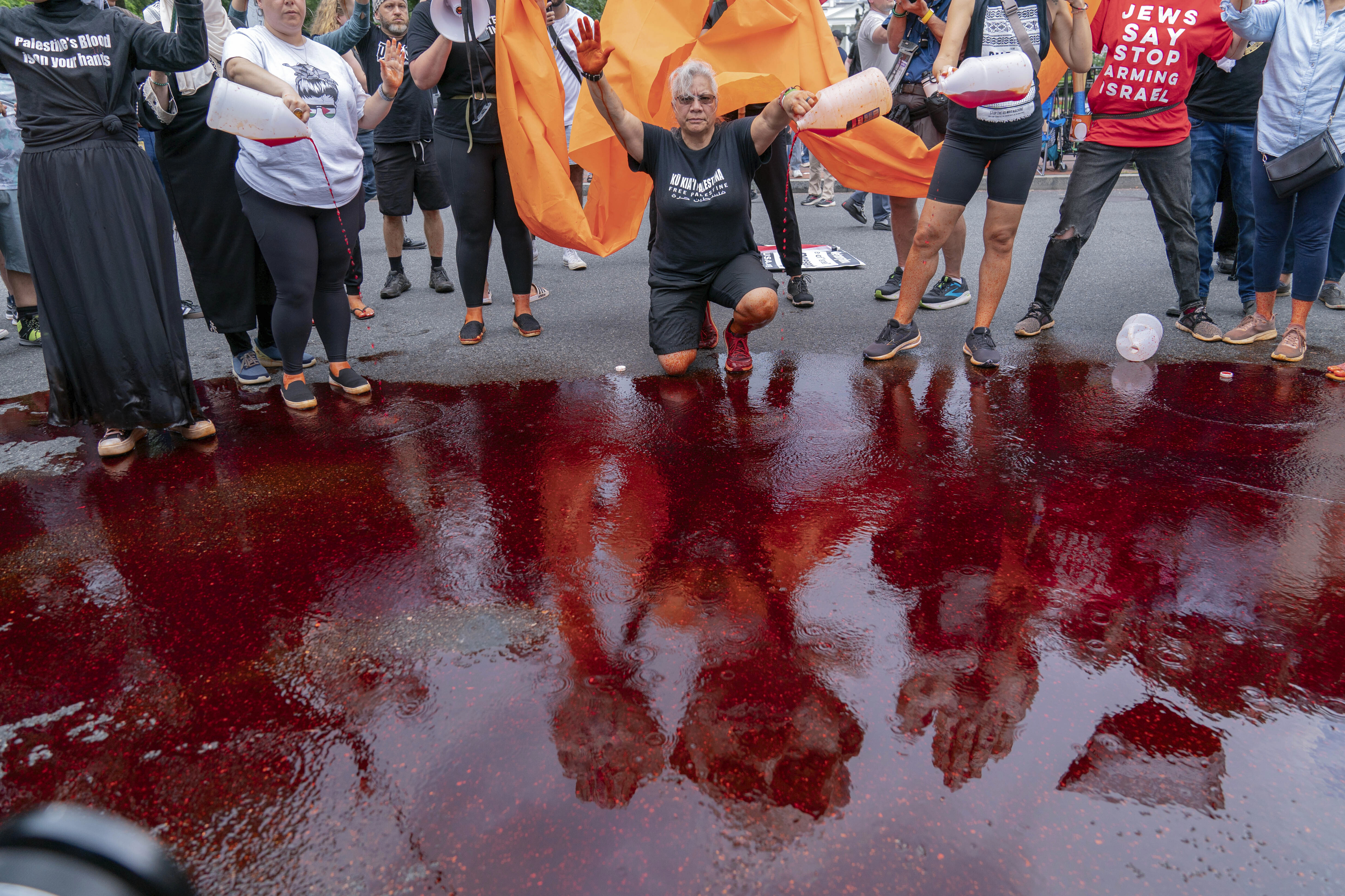 Demonstrators pour red liquid on the asphalt as they protest the visit of Israeli Prime Minister Benjamin Netanyahu to the White House during a rally at Lafayette Park, Thursday, July 25, 2024, in Washington. (AP Photo/Jose Luis Magana)