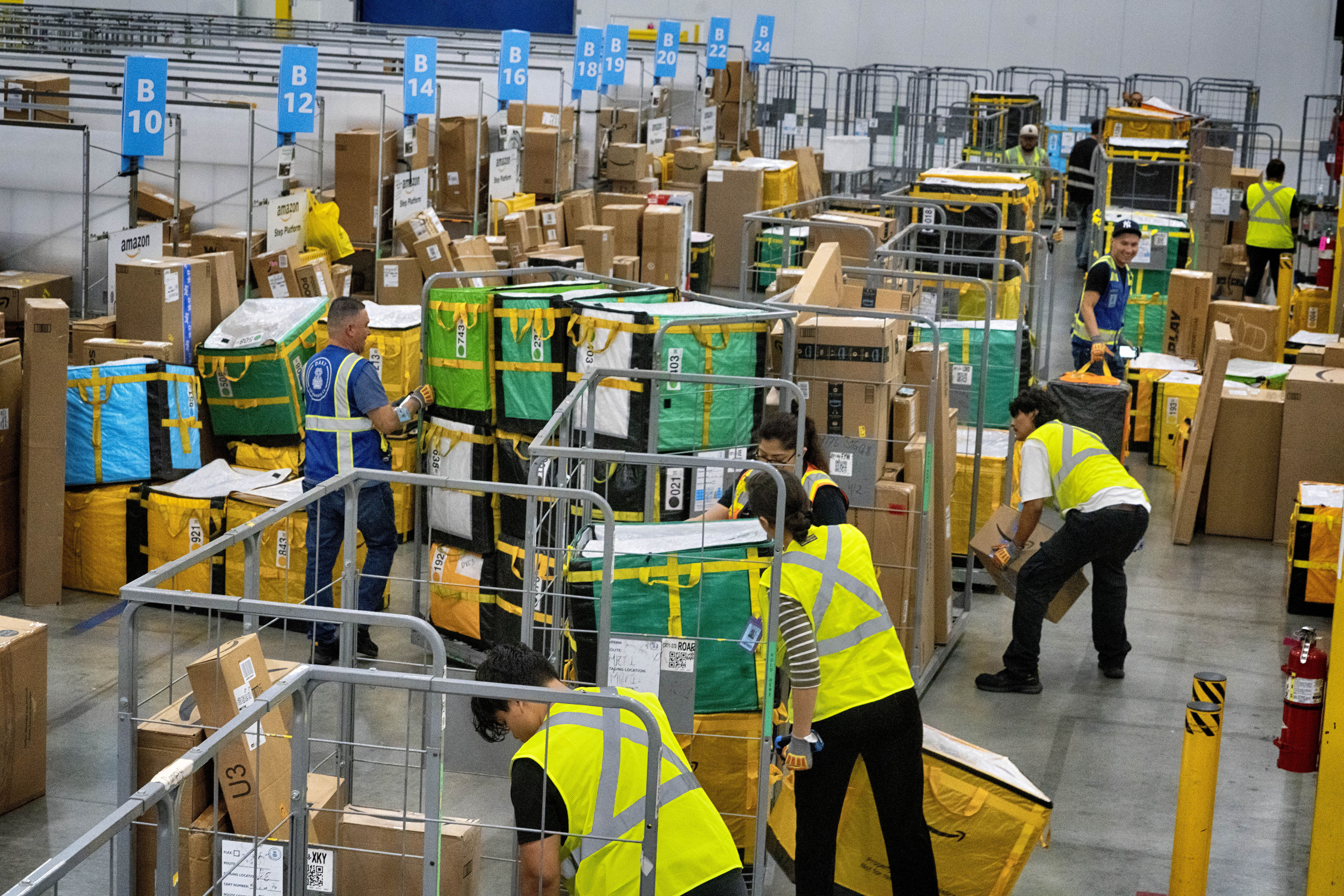 Amazon employees load packages on carts before being put on to trucks for distribution for Amazon's annual Prime Day event at an Amazon's DAX7 delivery station on Tuesday, July 16, 2024, in South Gate, Calif. (AP Photo/Richard Vogel)