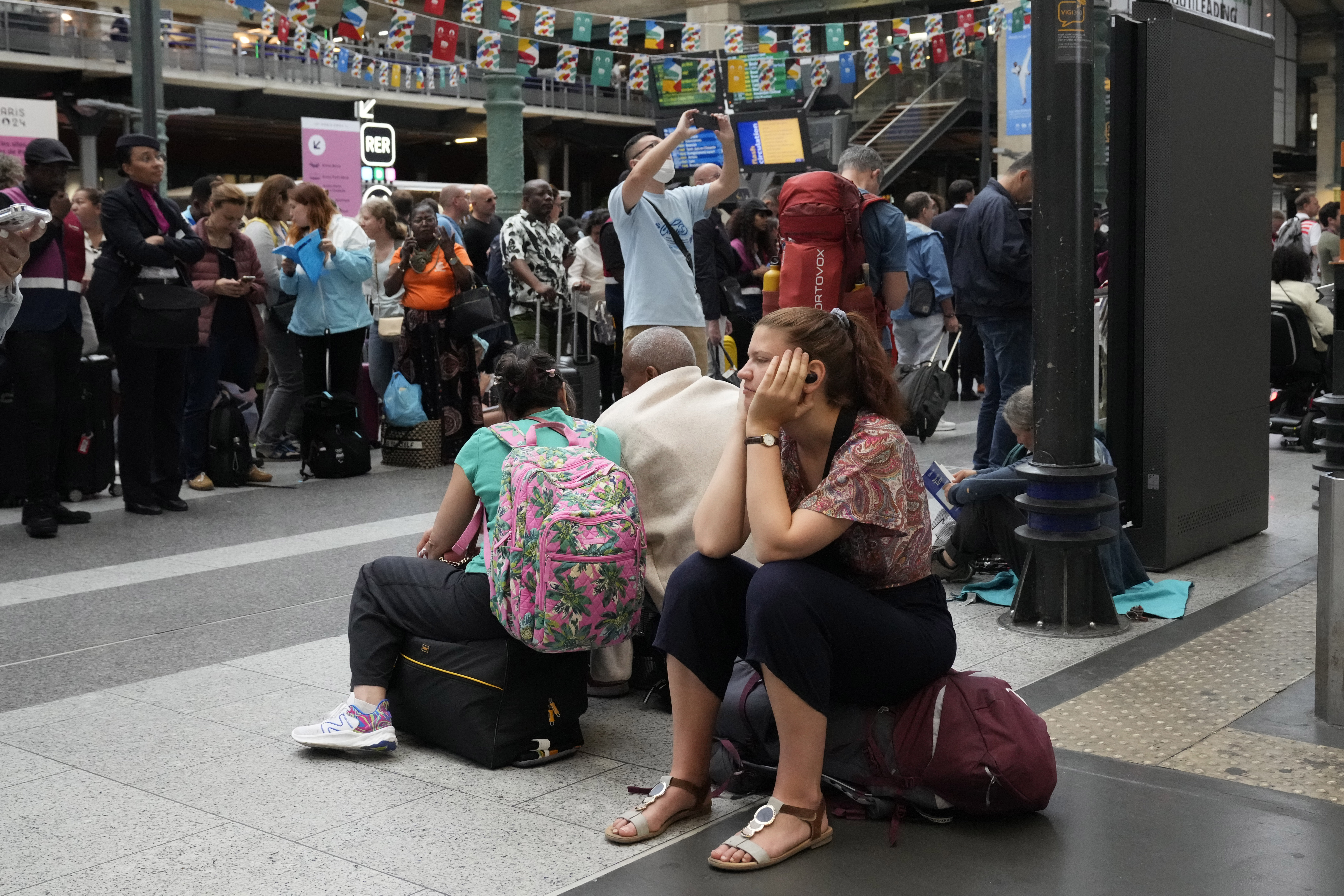 A traveler waits inside the Gare du Nord train station at the 2024 Summer Olympics, Friday, July 26, 2024, in Paris, France. Hours away from the grand opening ceremony of the Olympics, high-speed rail traffic to the French capital was severely disrupted on Friday by what officials described as "criminal actions" and sabotage. (AP Photo/Mark Baker)