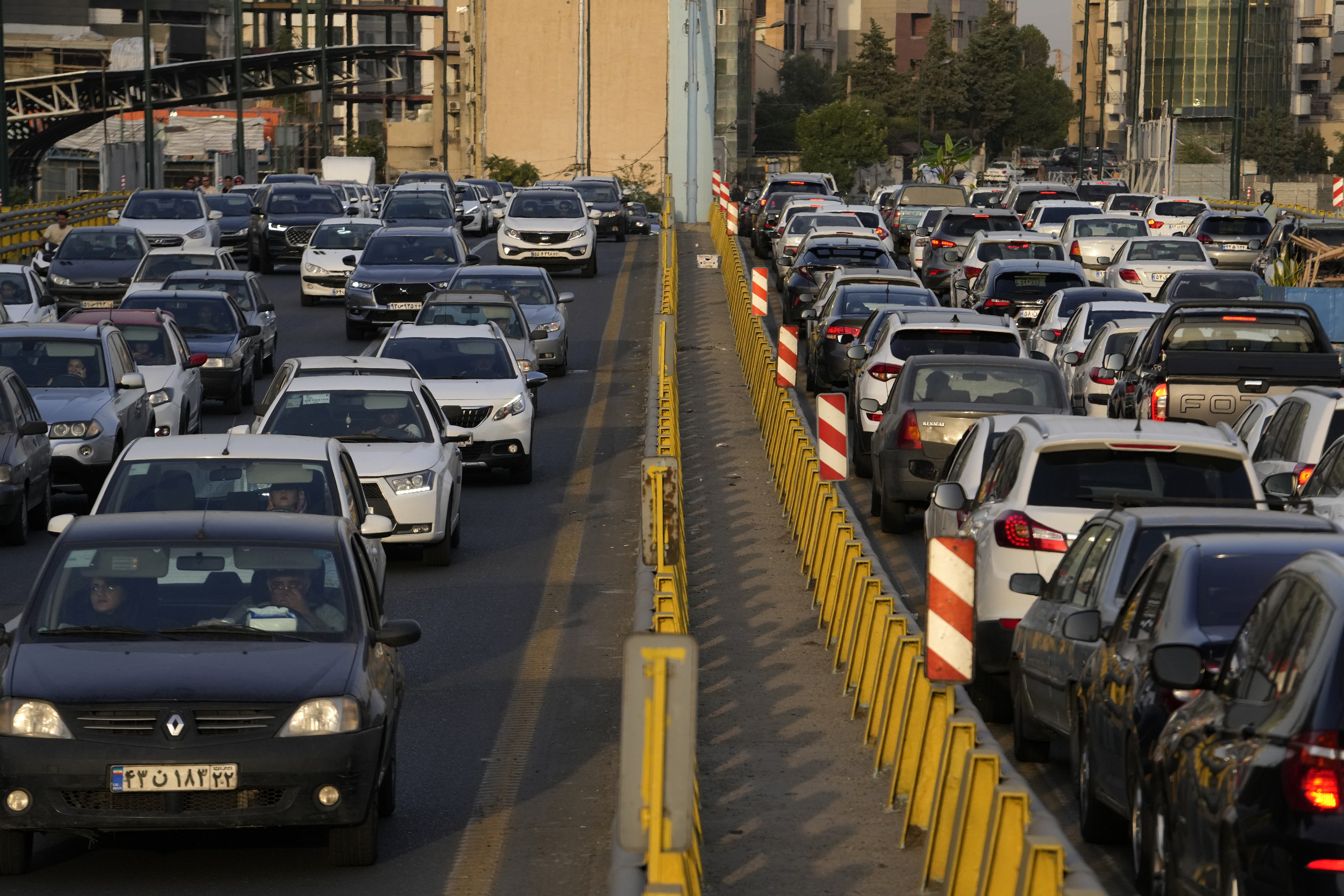 People commute in their cars during an afternoon traffic jam in northern Tehran, Iran, Tuesday, July 2, 2024. Comments suggesting that Iran's reformist presidential candidate could increase government-set gasoline prices have raised fears of a repeat of nationwide protests. (AP Photo/Vahid Salemi)