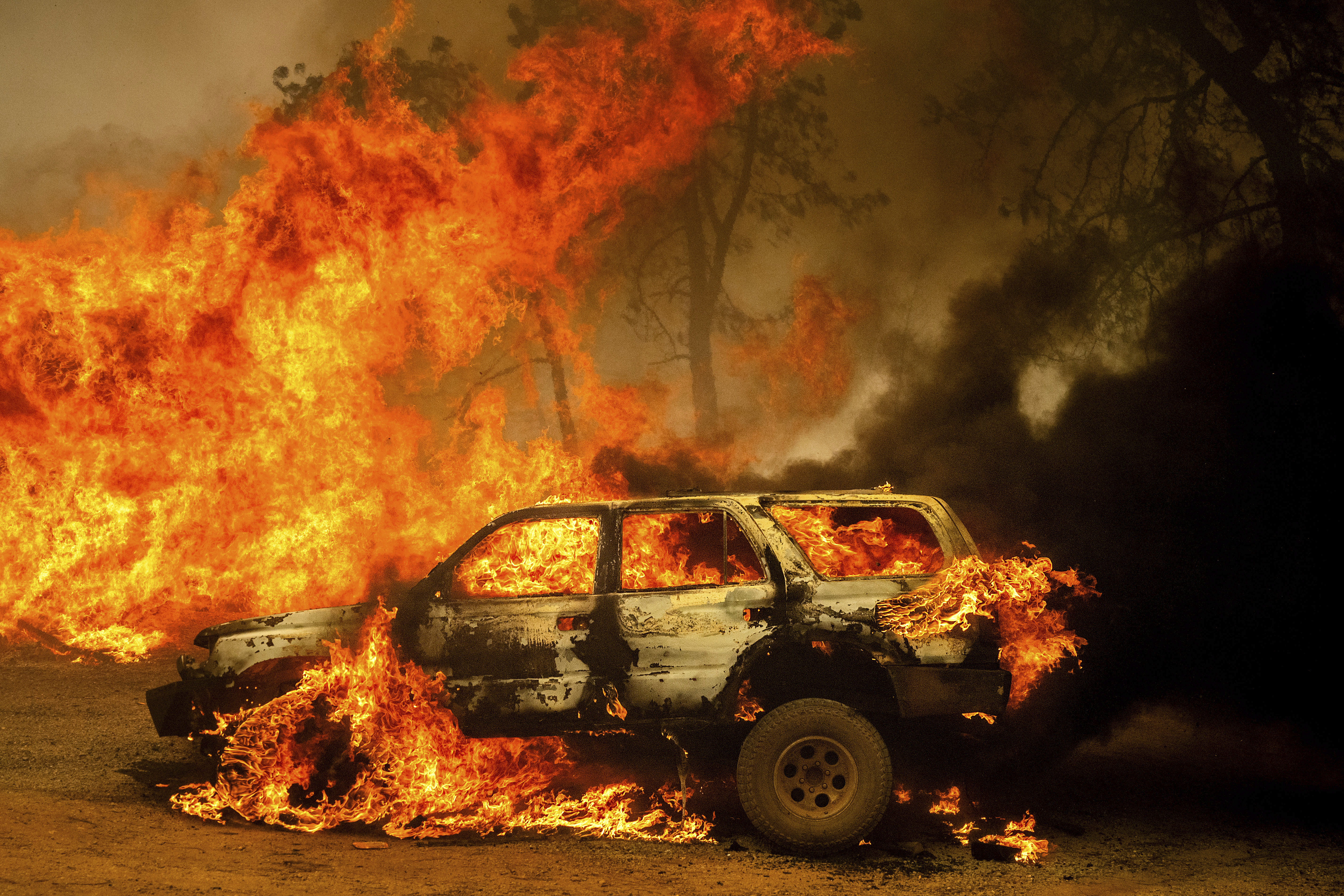 Flames consume a car and building as the Park Fire tears though the Cohasset community in Butte County, Calif., on Thursday, July 25, 2024. (AP Photo/Noah Berger)