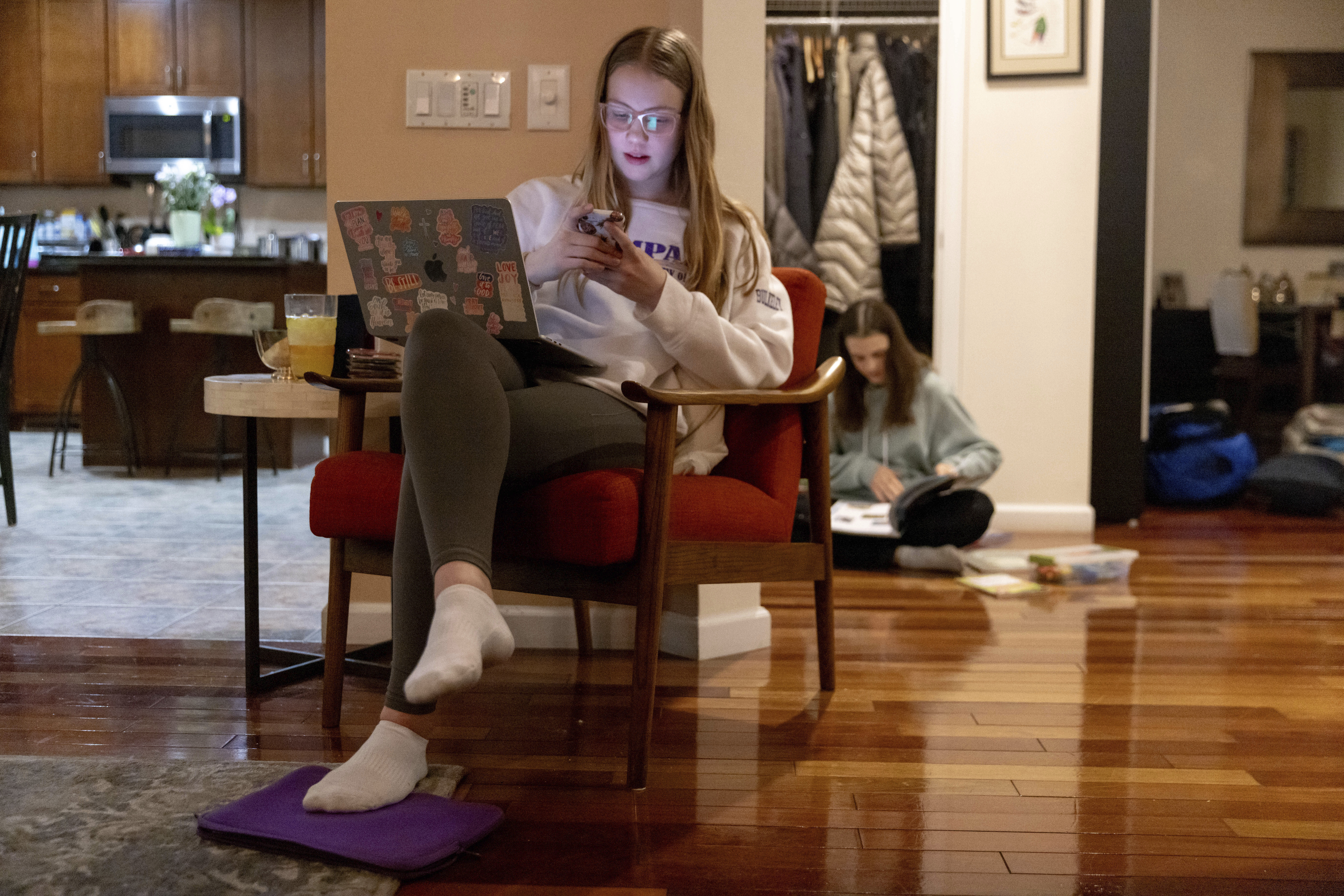 Kate Bulkeley uses her phone to print textbook pages while Sutton packs art materials ahead of a ski vacation, Friday, Feb. 16, 2024, in Westport, Conn. It is hard to be a teenager today without social media. For those trying to stay off social platforms at a time when most of their peers are immersed, the path can be challenging, isolating and at times liberating. It can also be life-changing. (AP Photo/Julia Nikhinson)