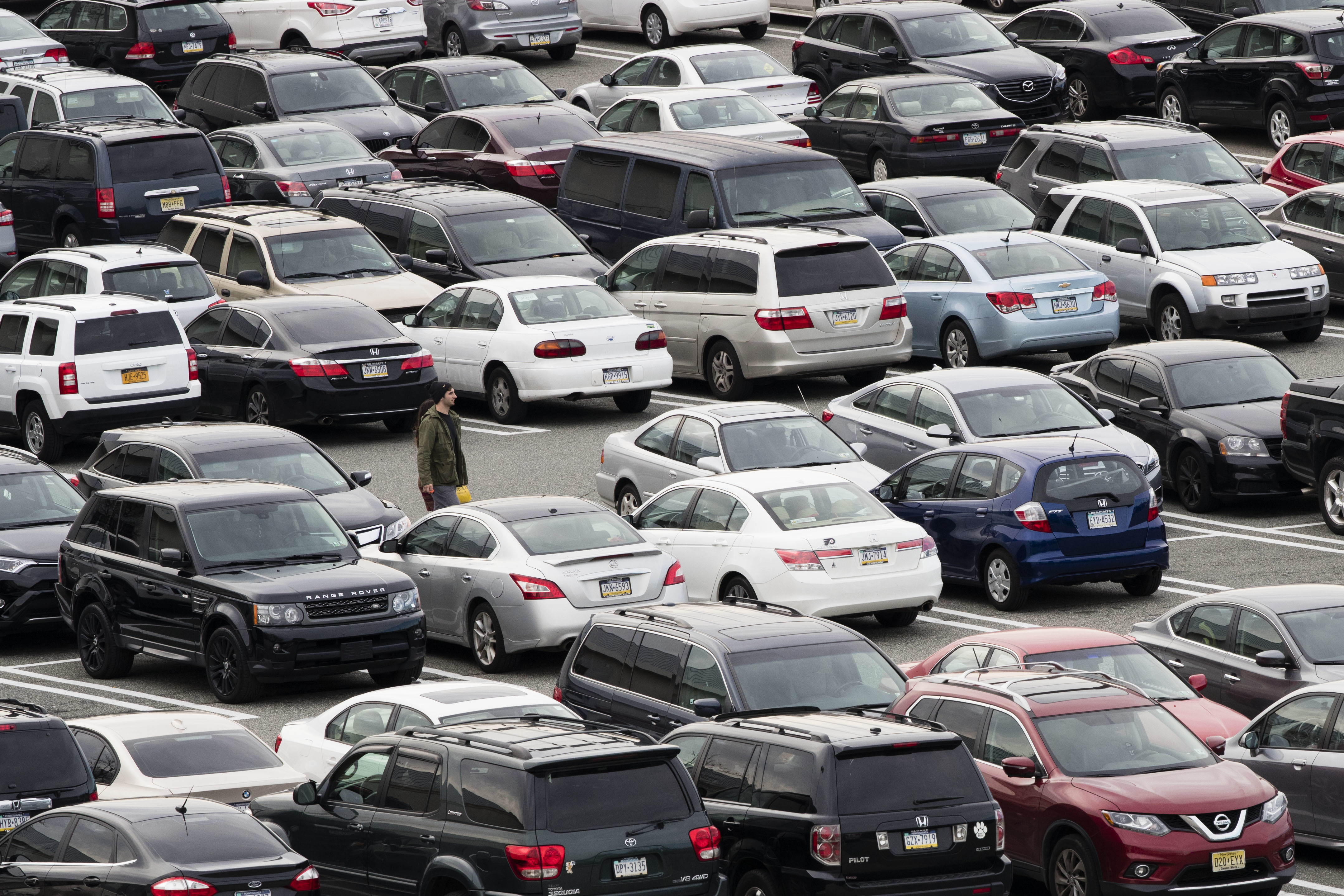 FILE - A person walks through a parking lot at a shopping mall on Dec. 8, 2016 in King of Prussia, Pa. Many newer cars use wireless key fobs and push-button starters. The technology makes it more convenient to get into your vehicle, but it also makes things easier for thieves. (AP Photo/Matt Rourke, File)