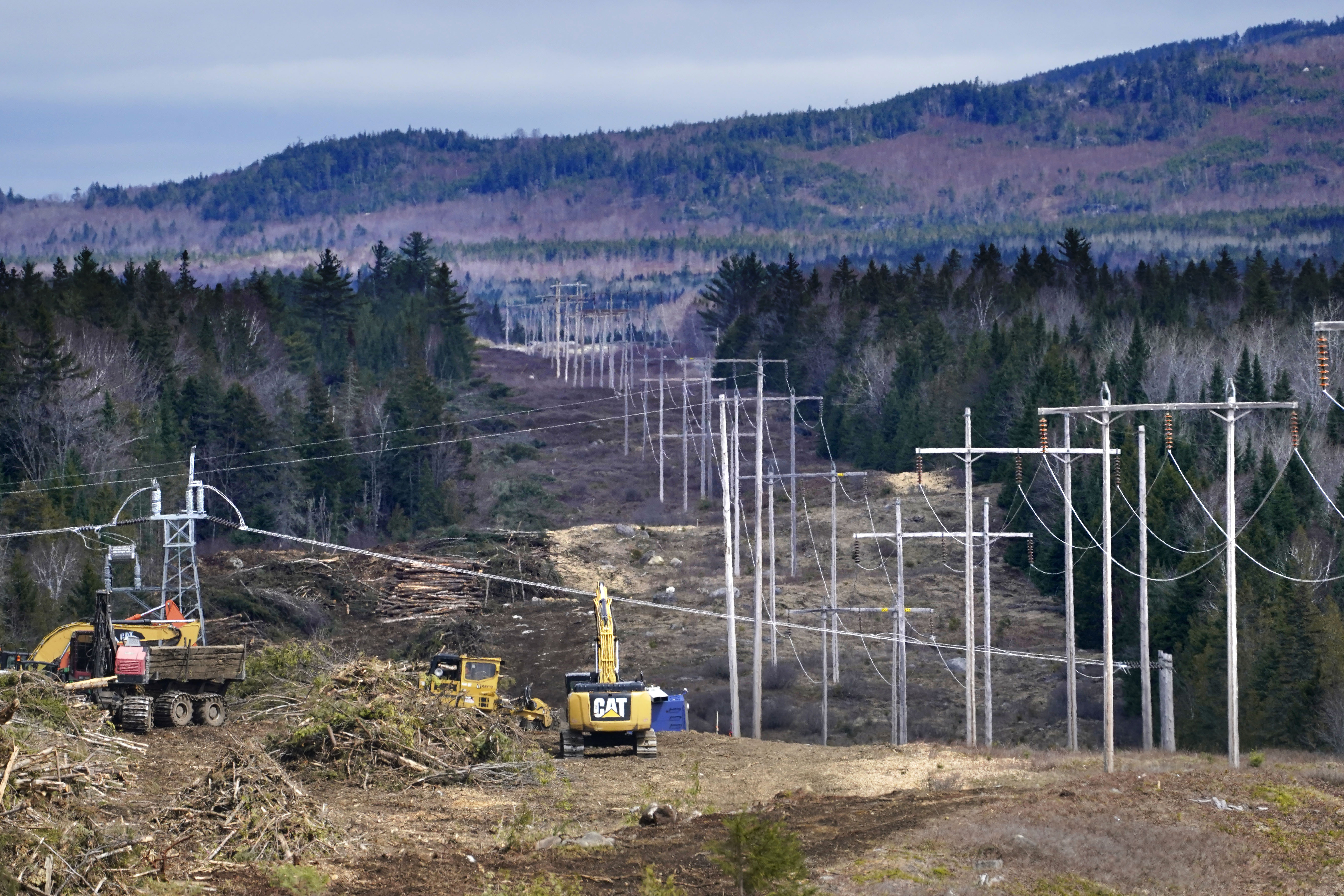 FILE - Heavy machinery is used to widen an existing Central Maine Power power line corridor to make way for new utility poles, April 26, 2021, near Bingham, Maine. A report filed with state regulators this week, July 2024, indicates workers have erected 441 poles, with wires installed on 178 of them, and progress is being made other parts of the project. (AP Photo/Robert F. Bukaty, File)