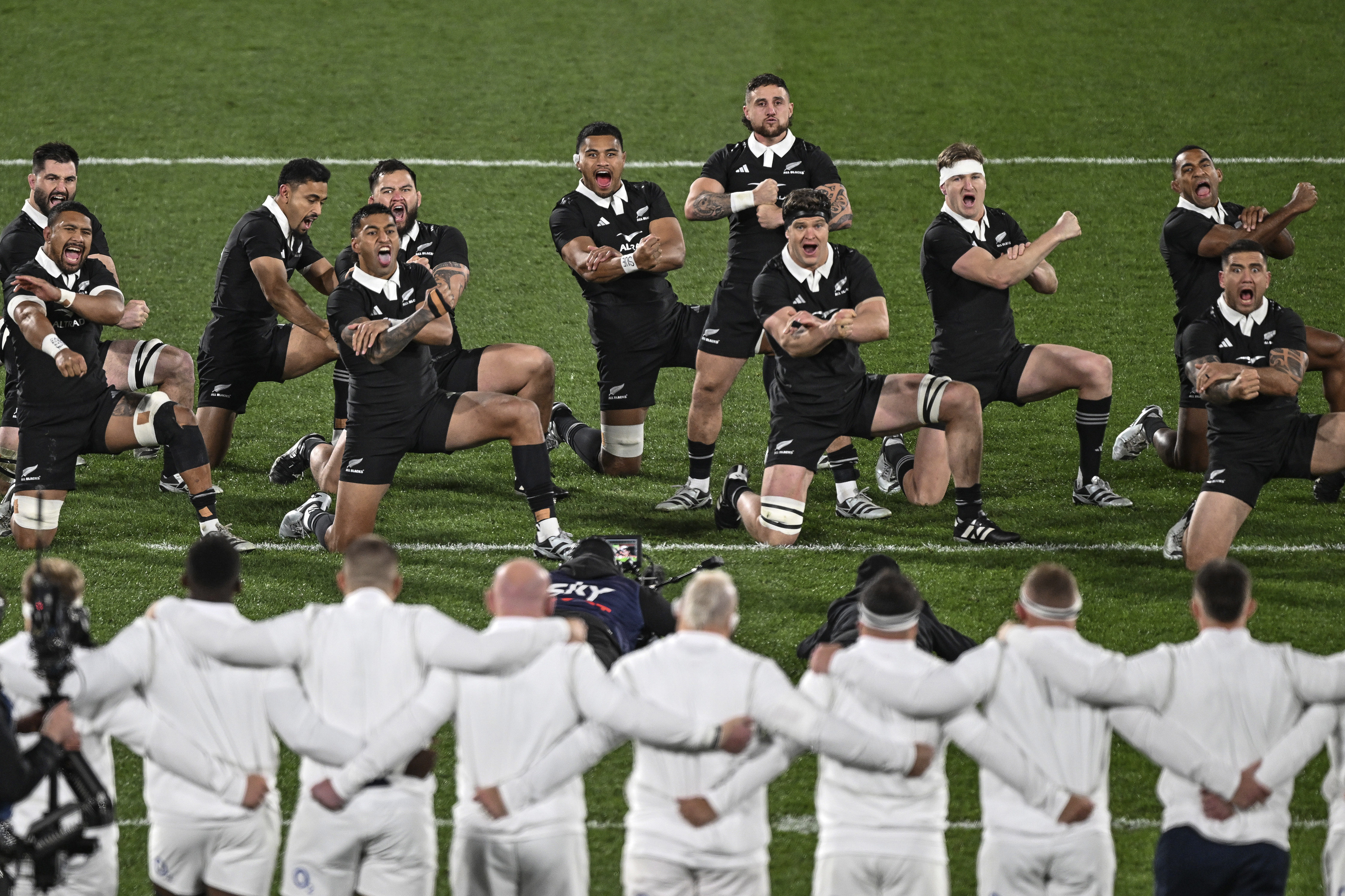 England's players lock arms as New Zealand perform the haka ahead of their rugby union test match in Dunedin, New Zealand, Saturday July 6, 2024. (Steve McArthur/Photosport via AP)