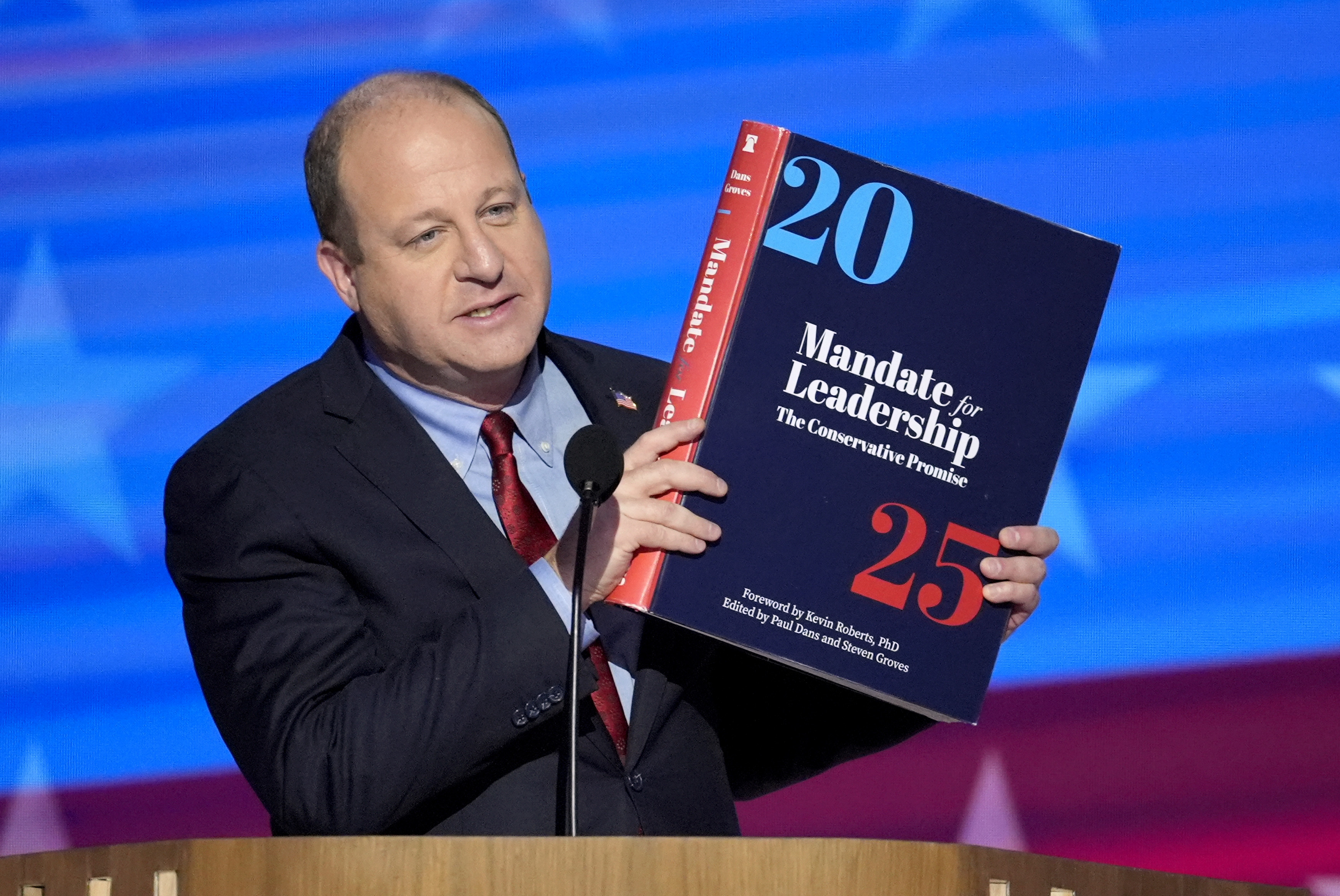 FILE - Colorado Gov. Jared Polis holds up a copy of Project 2025 as he speaks during the Democratic National Convention Aug. 21, 2024, in Chicago. (AP Photo/J. Scott Applewhite, File)