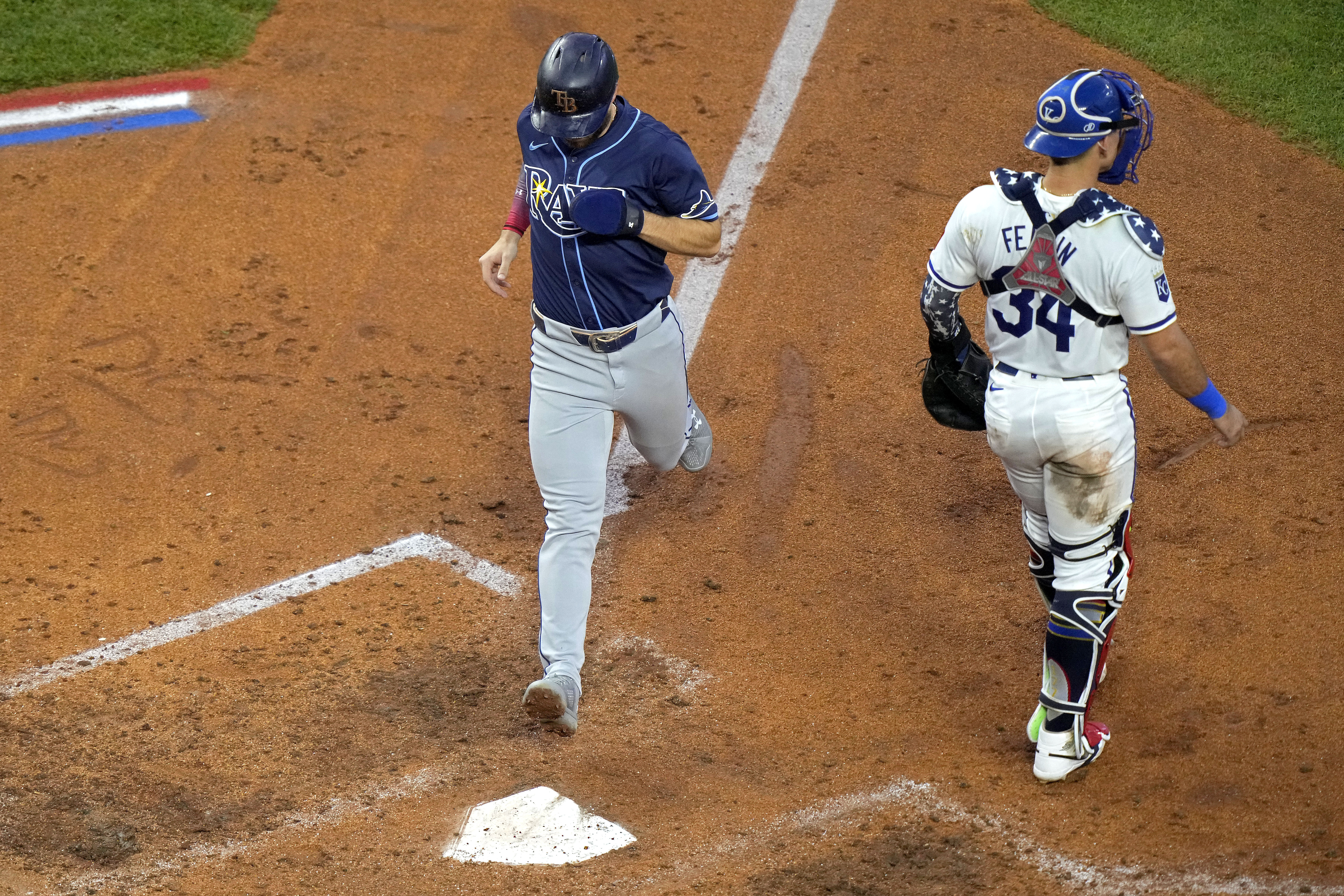 Tampa Bay Rays' Brandon Lowe runs home past Kansas City Royals catcher Freddy Fermin (34) to score on a sacrifice fly hit by Taylor Walls during the fifth inning of a baseball game Thursday, July 4, 2024, in Kansas City, Mo. (AP Photo/Charlie Riedel)