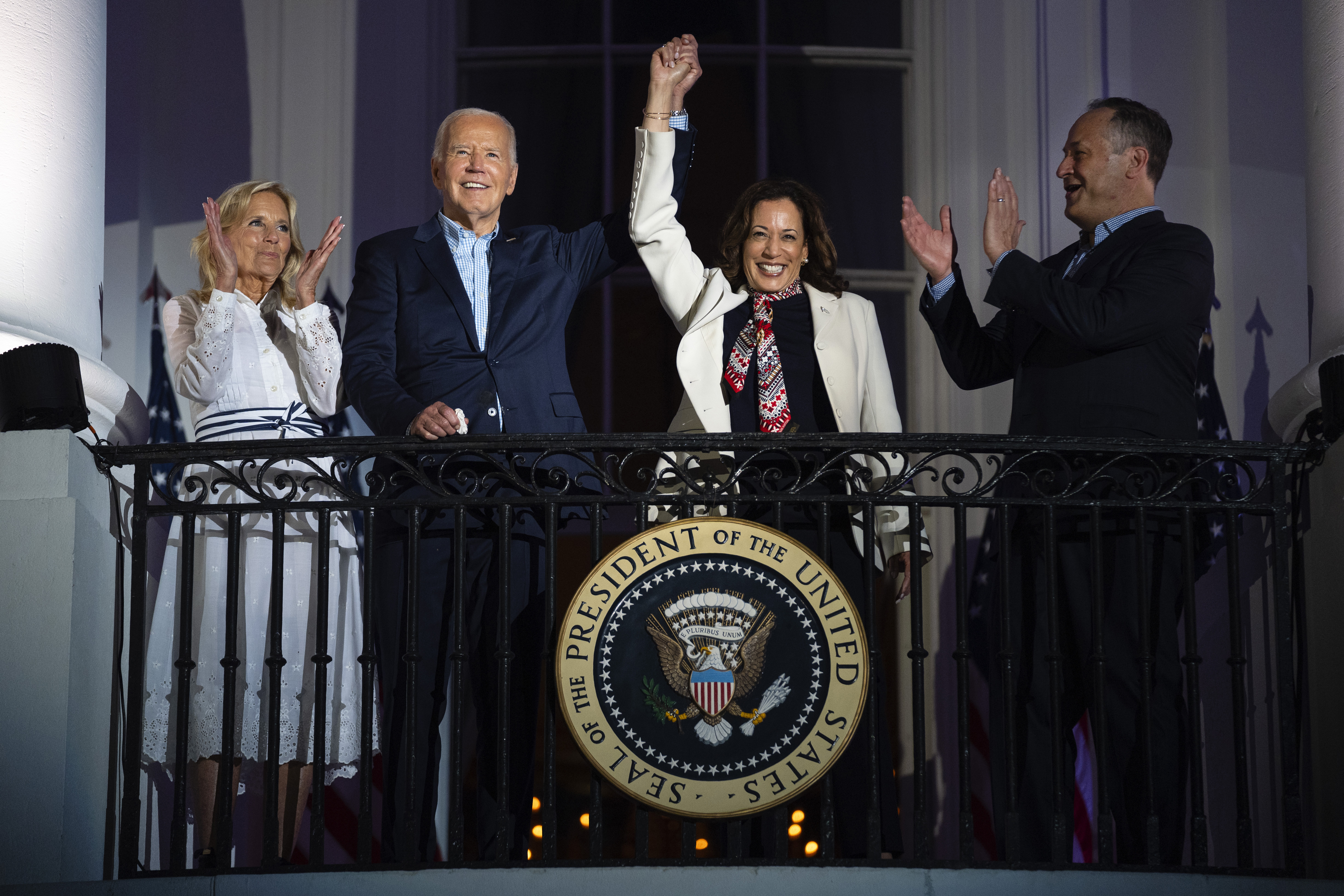 First lady Jill Biden, left, and second gentleman Douglass Emhoff, right, watch as President Joe Biden, center left, raises the hand of Vice President Kamala Harris from the balcony of the White House, July 4, 2024, in Washington. (AP Photo/Evan Vucci, File)