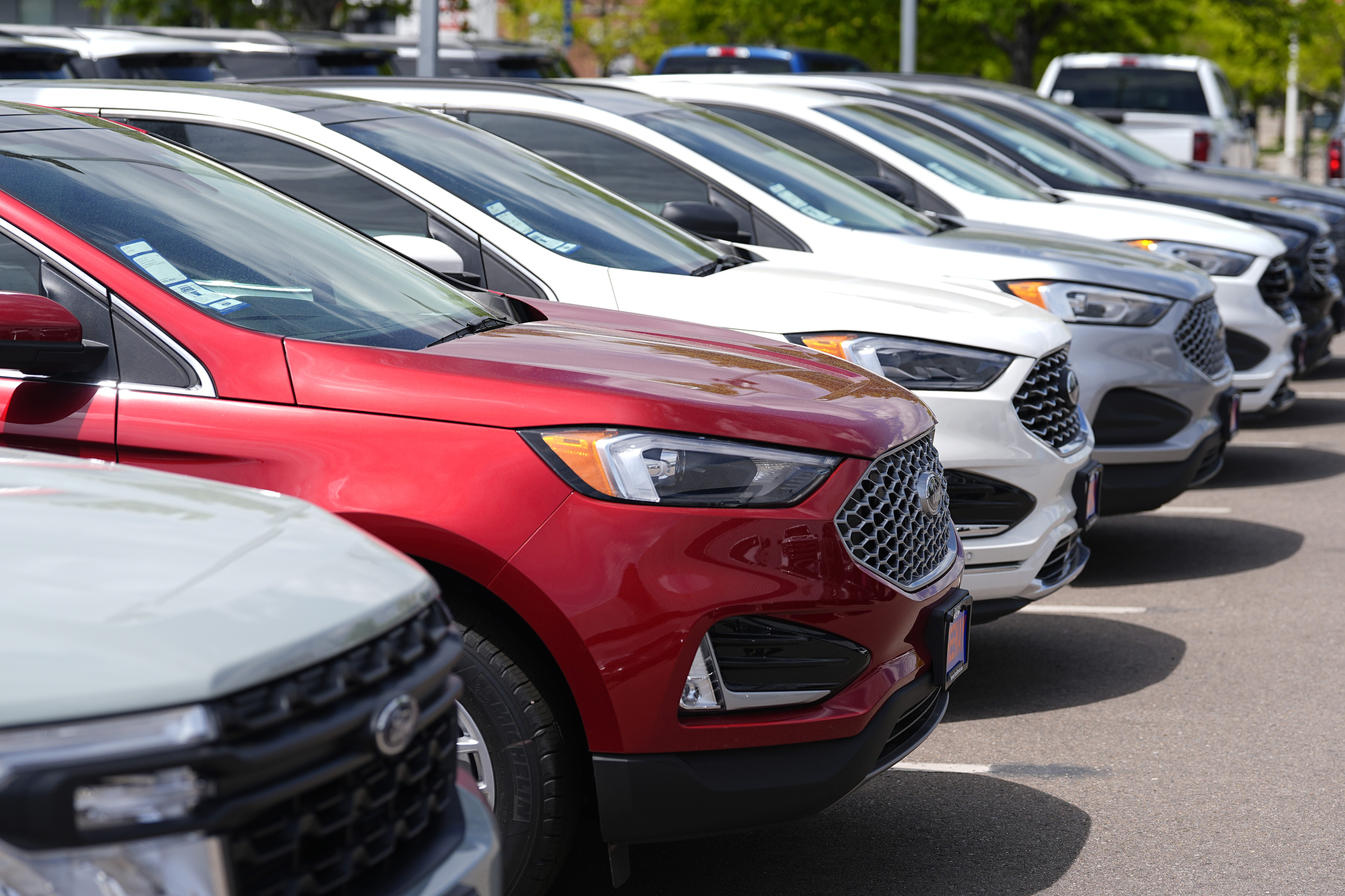 A line of unsold 2024 Edge utility vehicles sit at a Ford dealership Sunday, May 19, 2024, in Denver. Policymakers' willingness to keep their key rate at a two-decade peak — thereby keeping costs painfully high for mortgages, auto loans and other forms of consumer borrowing — carries its own risks.(AP Photo/David Zalubowski)