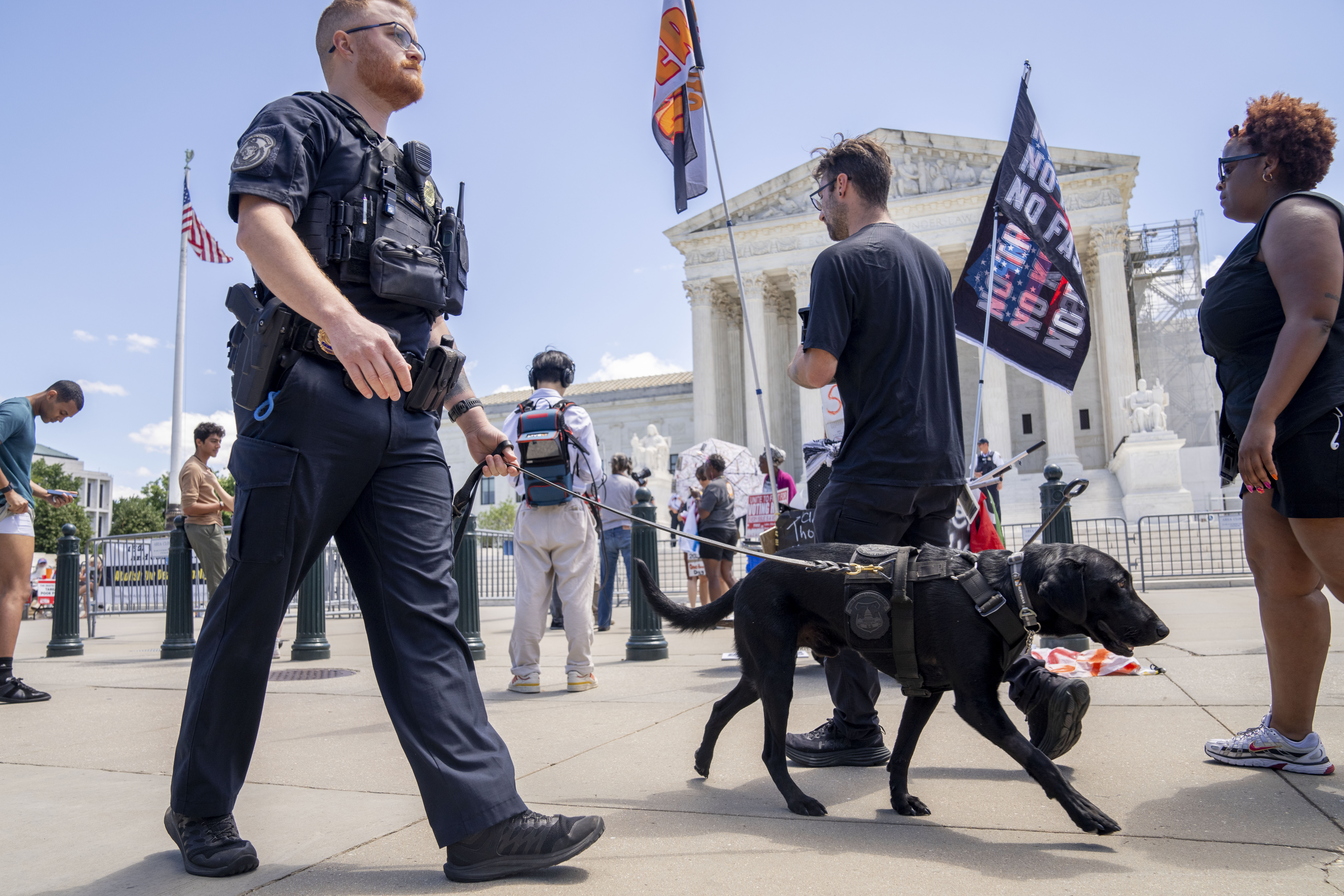 A U.S. Capitol Police officer and K-9 patrol pass protesters by the Supreme Court, Monday, July 1, 2024, after court decisions were announced in Washington. (AP Photo/Jacquelyn Martin)