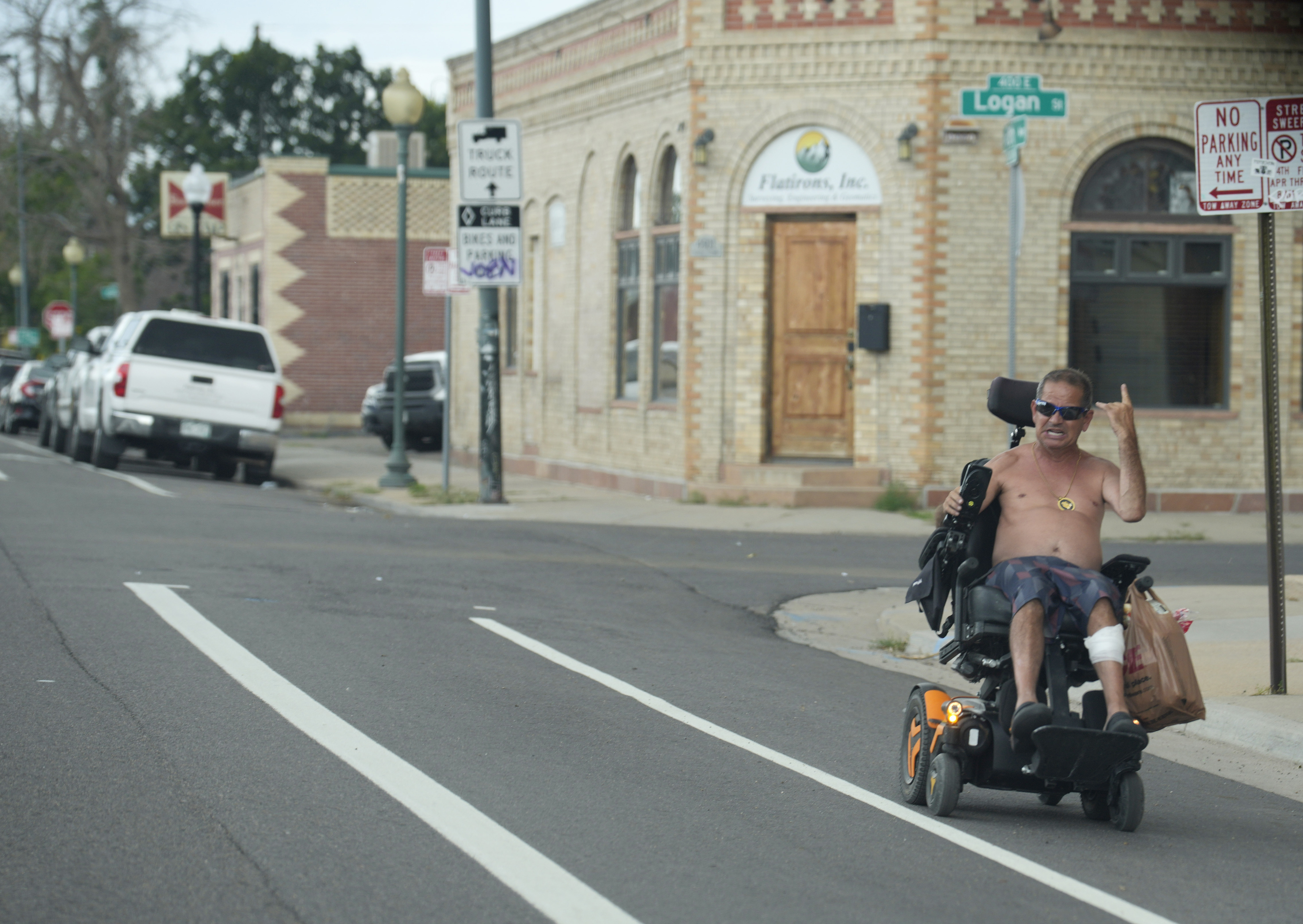 A shirtless man guides his wheelchair down the bicycle lane along 45th Avenue as tempratures rise toward triple digits in the Globeville neighborhood Wednesday, July 26, 2023, in north Denver. (AP Photo/David Zalubowski)