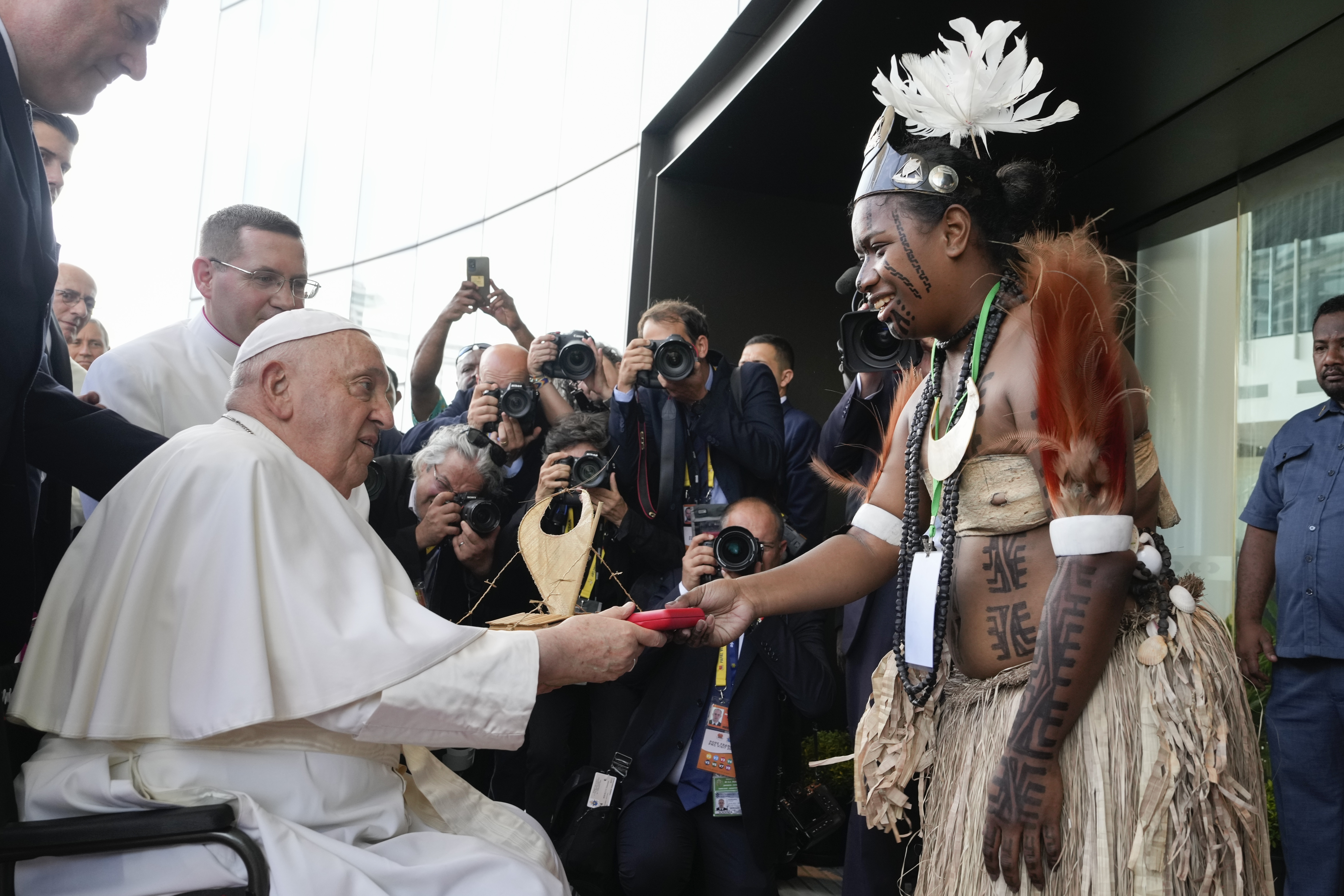 Pope Francis hands a gift to a traditional dancer as he arrives at APEC Haus in Port Moresby, Papua New Guinea, Saturday, Sept. 7, 2024. (AP Photo/Mark Baker)