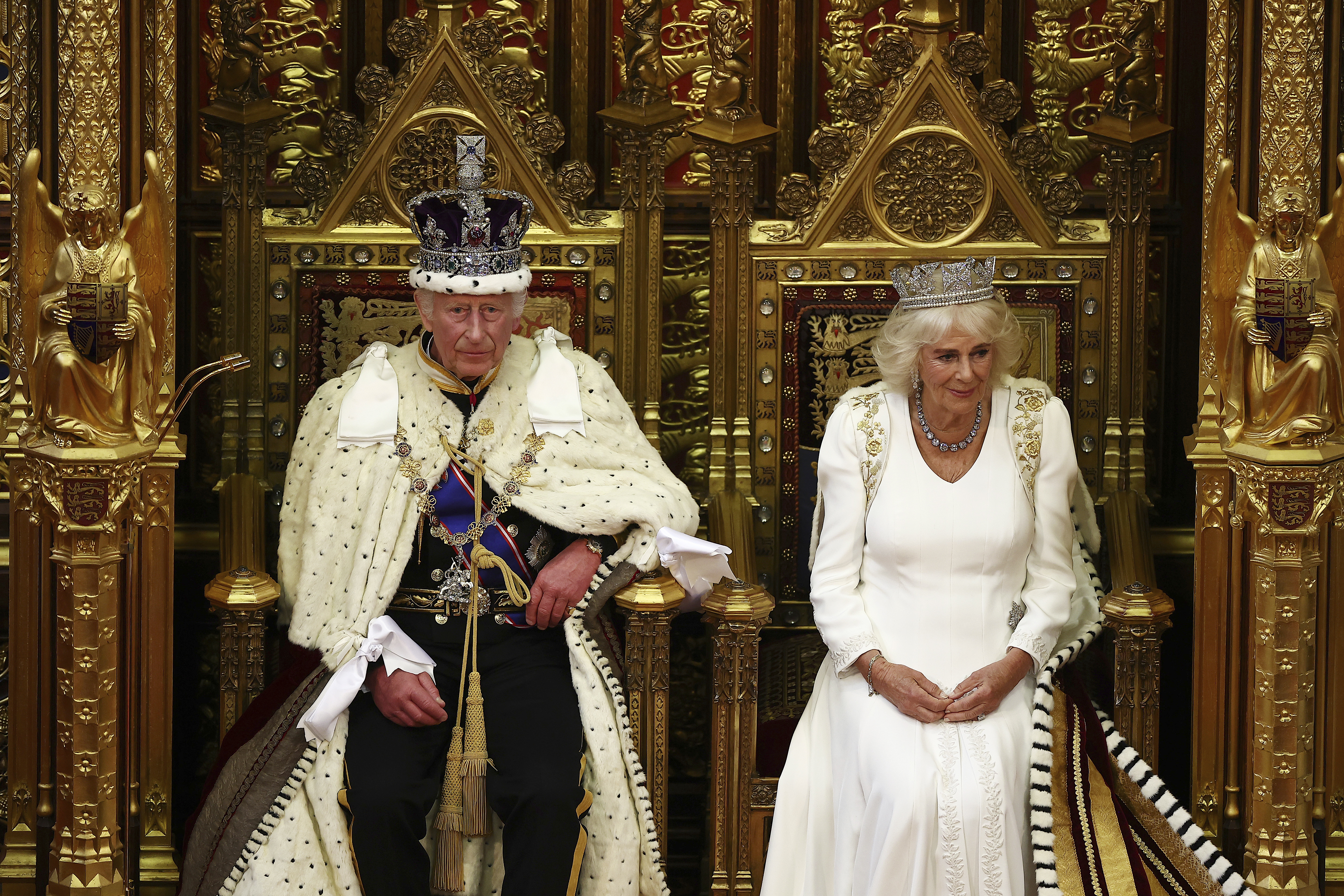 Britain's King Charles III, wearing the Imperial State Crown and the Robe of State, sits alongside Britain's Queen Camilla, wearing the George IV State Diadem, before reading the King's Speech from the The Sovereign's Throne in the House of Lords chamber, during the State Opening of Parliament, at the Houses of Parliament, in London, Wednesday, July 17, 2024. (Henry Nicholls/POOL via AP)