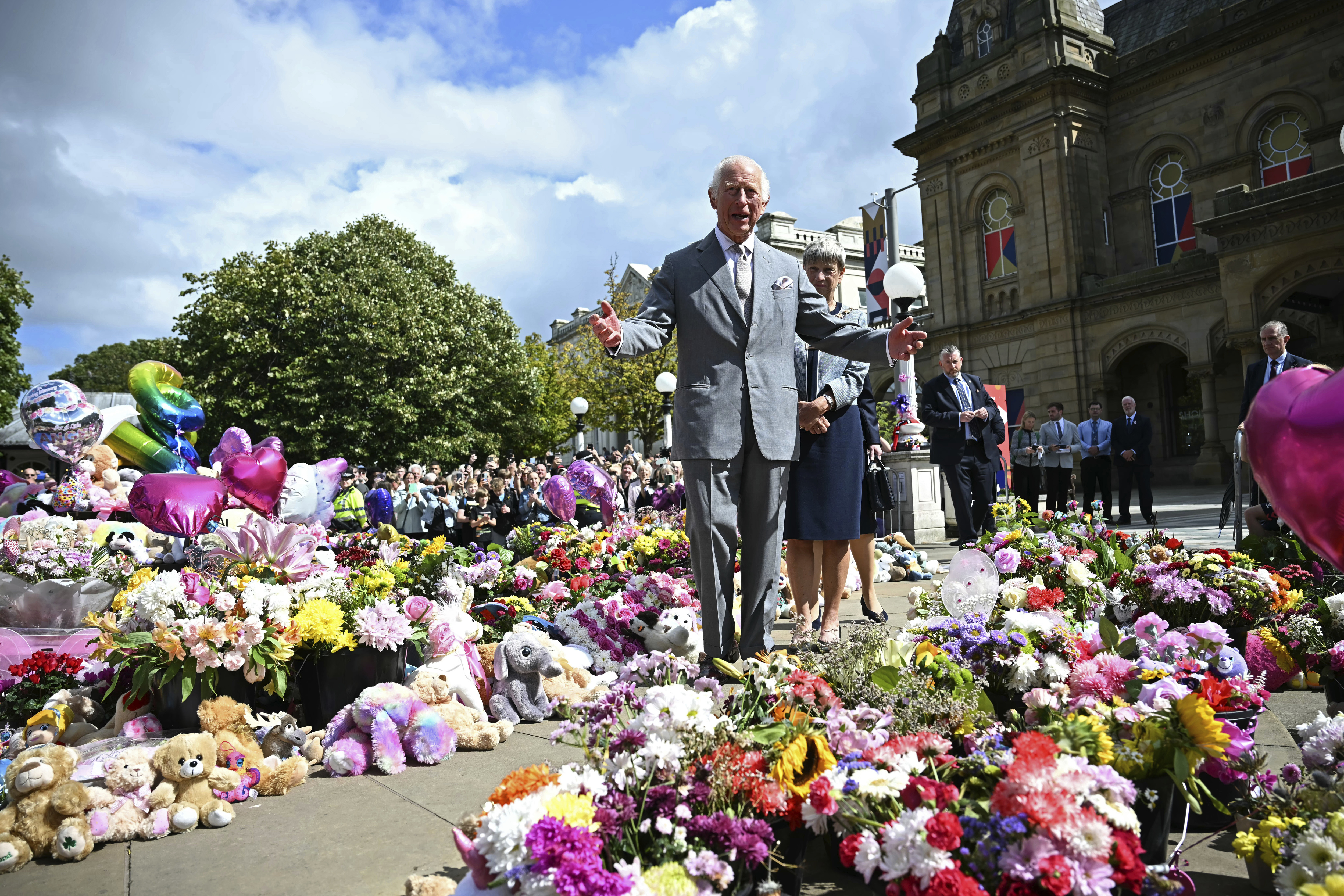 Britain's King Charles III looks at the tributes outside Southport Town Hall, in Southport, England, Tuesday Aug. 20, 2024, as he meets members of the local community, following the July 29 attack at a children's dance party. (Paul Ellis/Pool via AP)