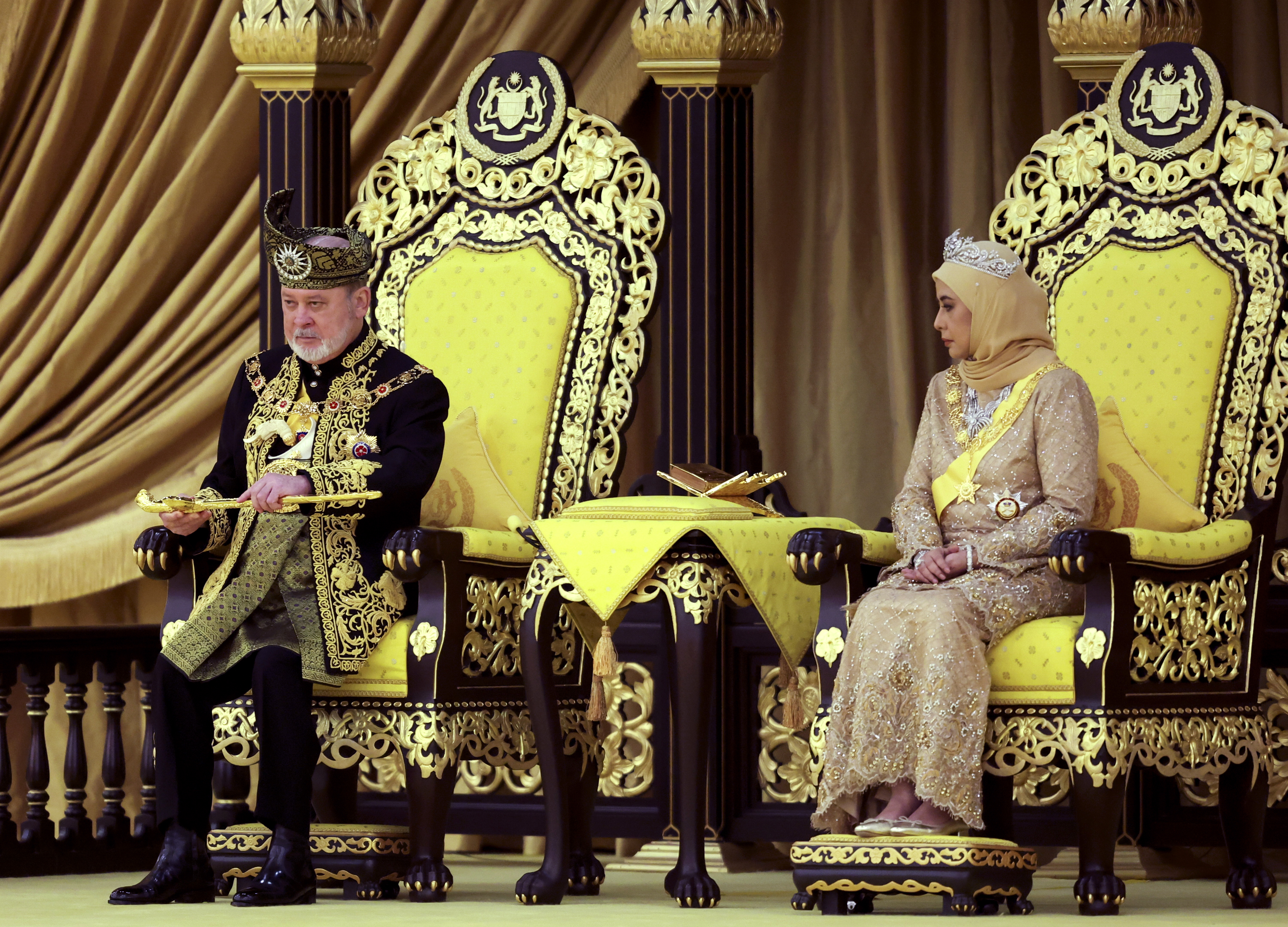 The 17th King of Malaysia, Sultan Ibrahim Iskandar, left, lifts a ceremonial dagger as Queen Raja Zarith Sofiah looks on during his coronation at the National Palace in Kuala Lumpur, Malaysia, Saturday, July 20, 2024. (Hasnoor Hussain/Pool Photo via AP)