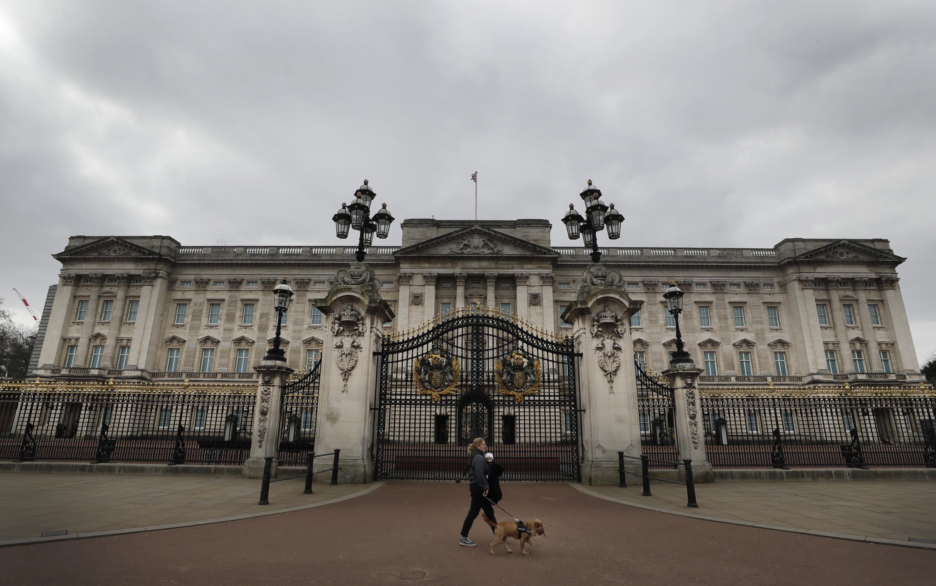 FILE - A dog walker passes a quiet Buckingham Palace, in London, March 23, 2021. Royal accounts show the British monarchy’s publicly-funded spending rose to 102.4 million pounds ($124 million) in the past year, with the renovation of Buckingham Palace taking up a large part of the expenses. The palace’s annual Sovereign Grant report showed that royal spending went up by 14.9 million pounds, or 17%, compared to the previous year, a report published Thursday, June 30, 2022 showed. (AP Photo/Kirsty Wigglesworth, file)