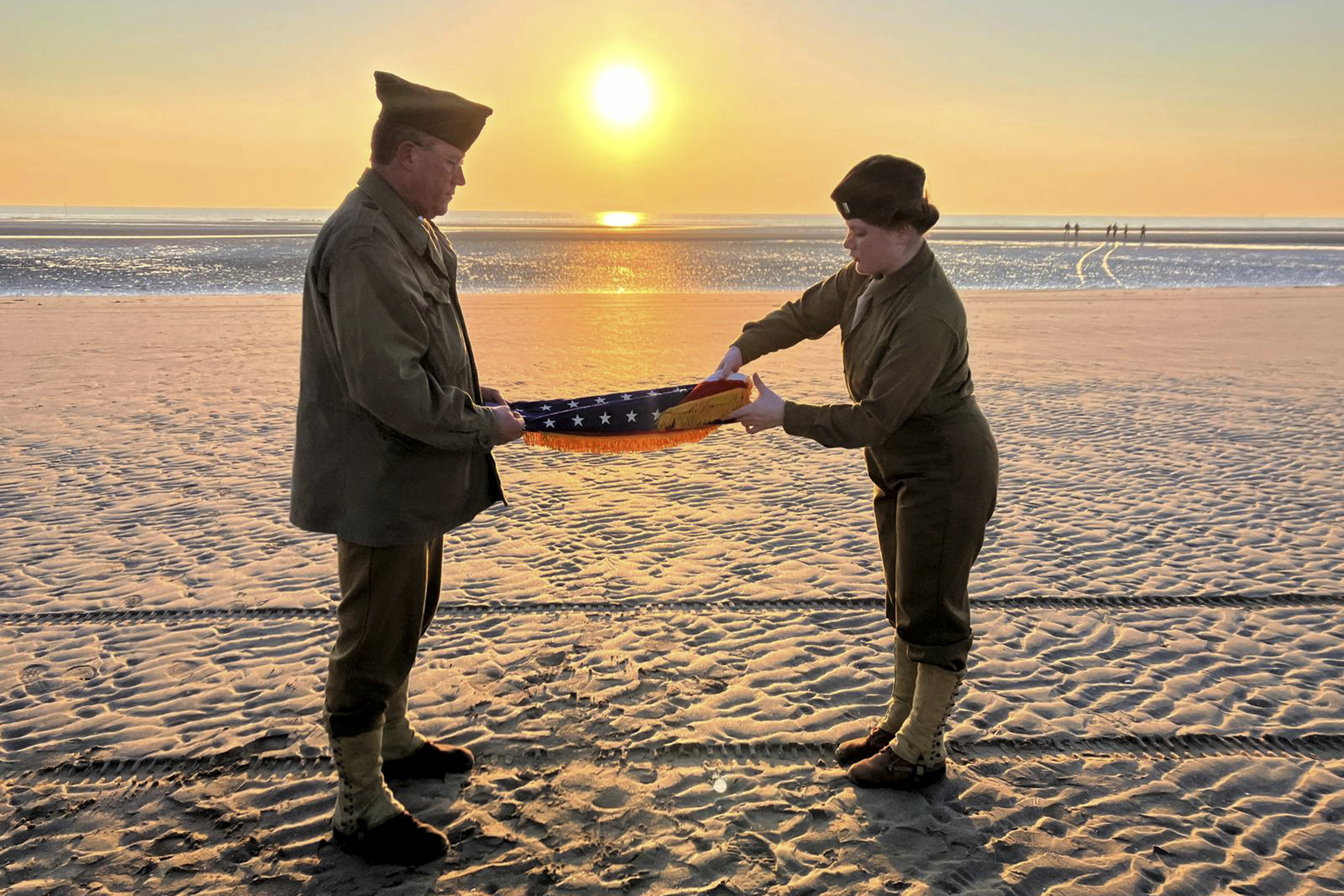 Christophe Receveur and his daughter Julie, of France, unfold an American flag he bought six month ago in Gettysburg, Penn., to mark D-Day, Thursday, June 6, 2024 on Utah Beach, Normandy. As the sun sets on the D-Day generation, it's rising again over Normandy beaches where soldiers fought and died exactly 80 years ago, kicking off intense anniversary commemorations Thursday against the backdrop of renewed war in Europe, in Ukraine. (AP Photo/John Leicester)