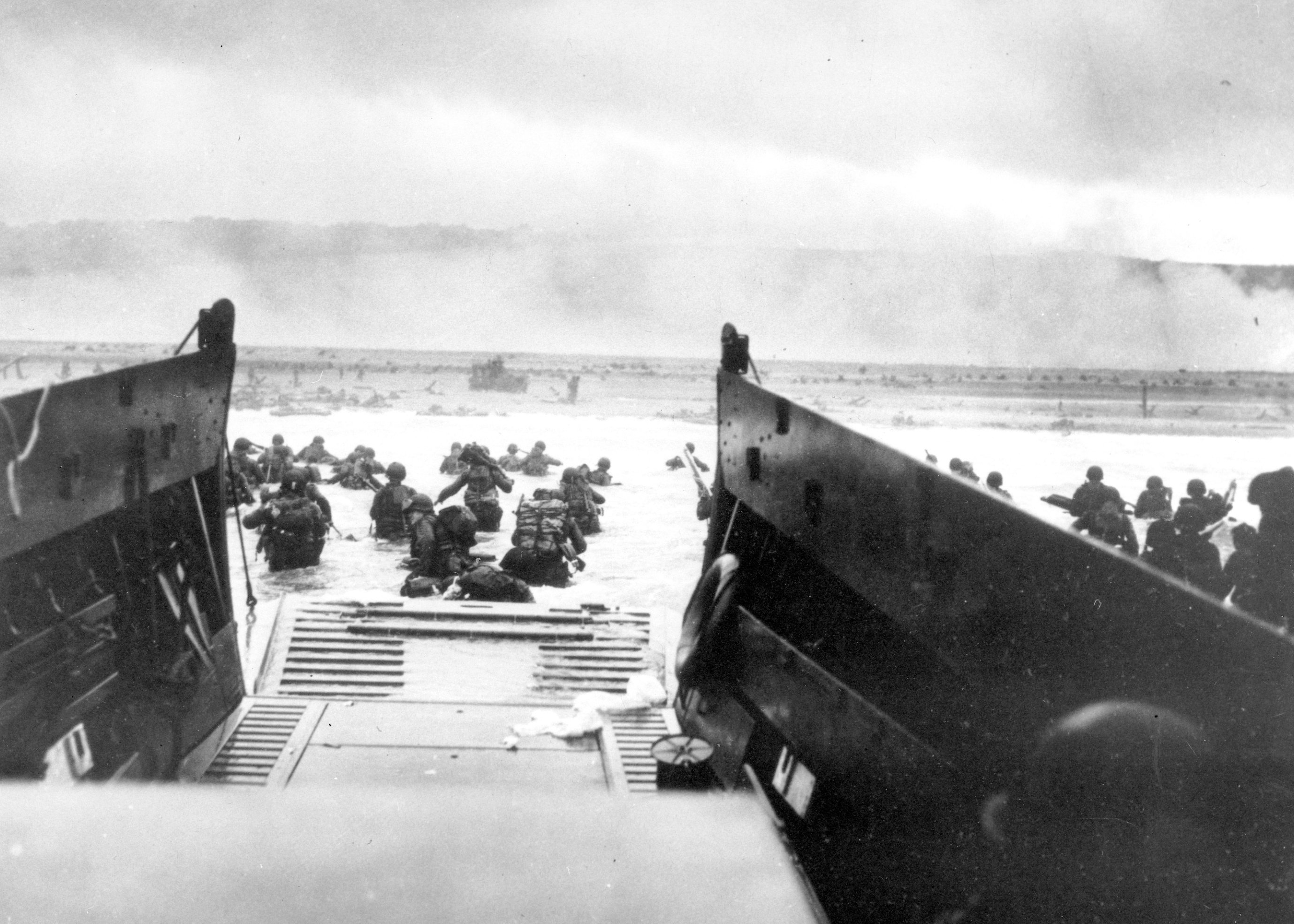 FILE - In this June 8, 1944, file photo, under heavy German machine gun fire, American infantrymen wade ashore off the ramp of a Coast Guard landing craft during the invasion of the French coast of Normandy in World War II. June 6, 2019, marks the 75th anniversary of D-Day, the assault that began the liberation of France and Europe from German occupation, leading to the end World War II. (U.S. Coast Guard via AP, File)